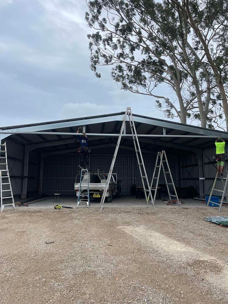 Man Standing On A Ladder In Front Of A Building — Providing Steel & Concrete Construction In Gold Coast, QLD