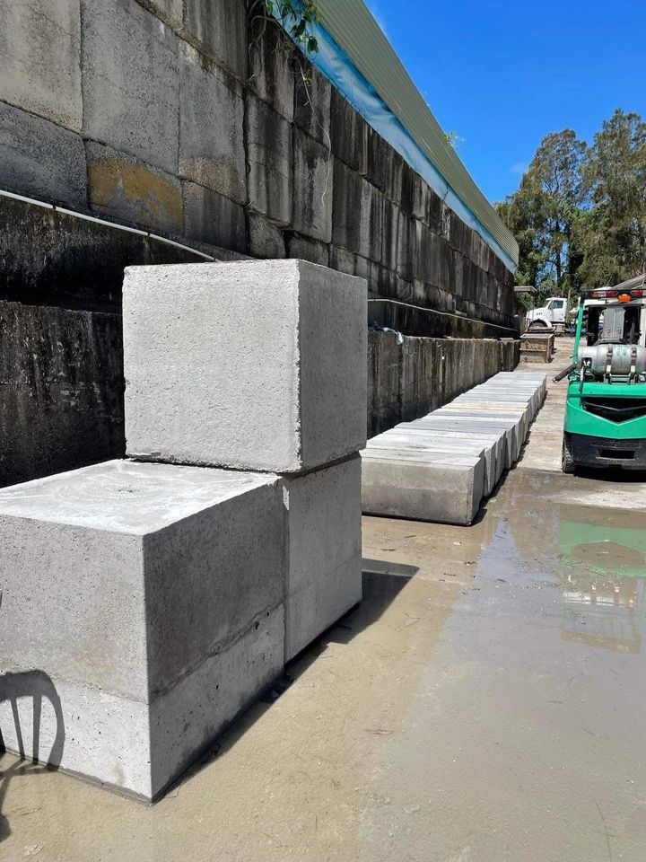 A Green Forklift is Carrying a Stack of Concrete Blocks — Providing Steel & Concrete Construction In Eviron, NSW