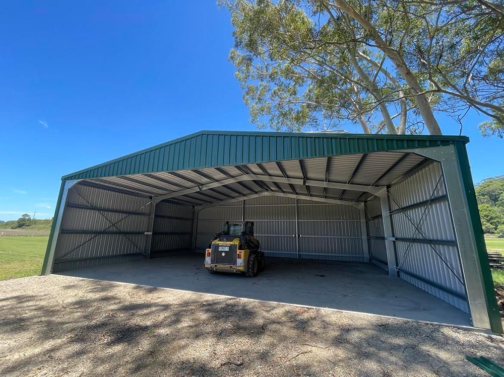 A Bulldozer Is Parked In A Shed With A Green Roof  —CJR Group Concrete Construction In Tweed Heads, NSW