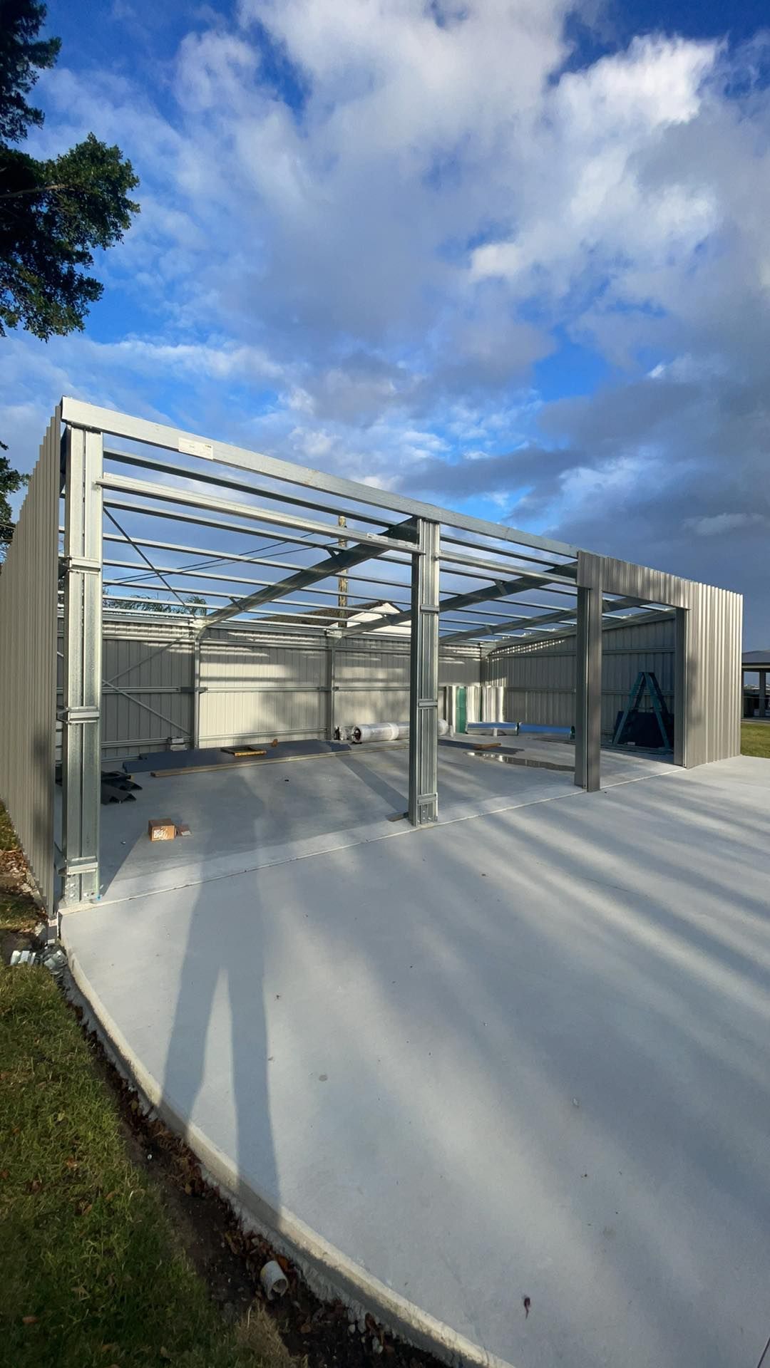 Large Metal Structure Being Built Next to a Concrete Driveway — Providing Steel & Concrete Construction in Eviron, NSW