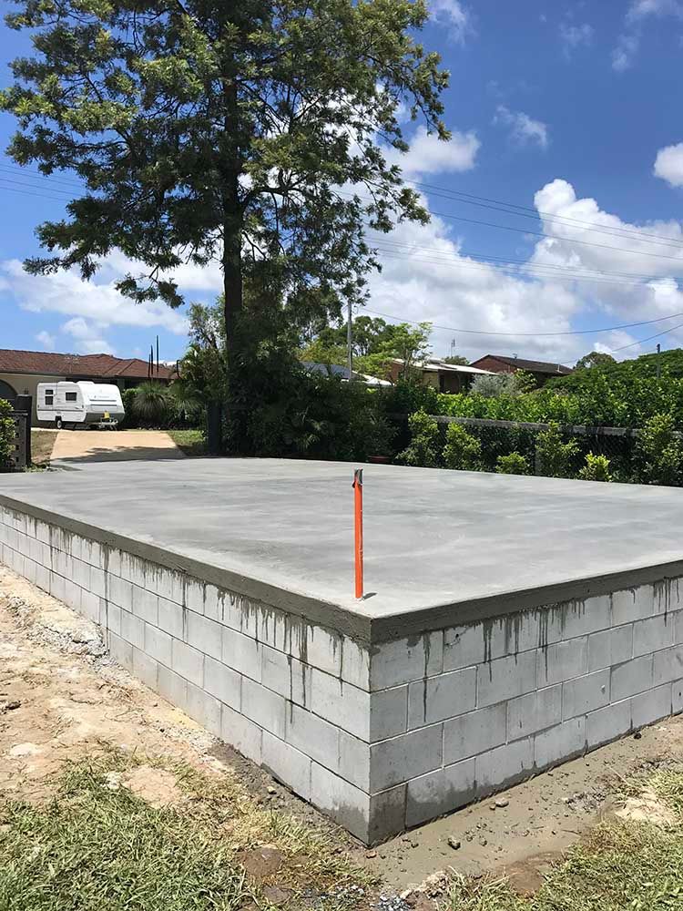 Concrete Foundation Is Being Built In A Yard With A Tree In The Background — Providing Steel & Concrete Construction In Gold Coast, QLD