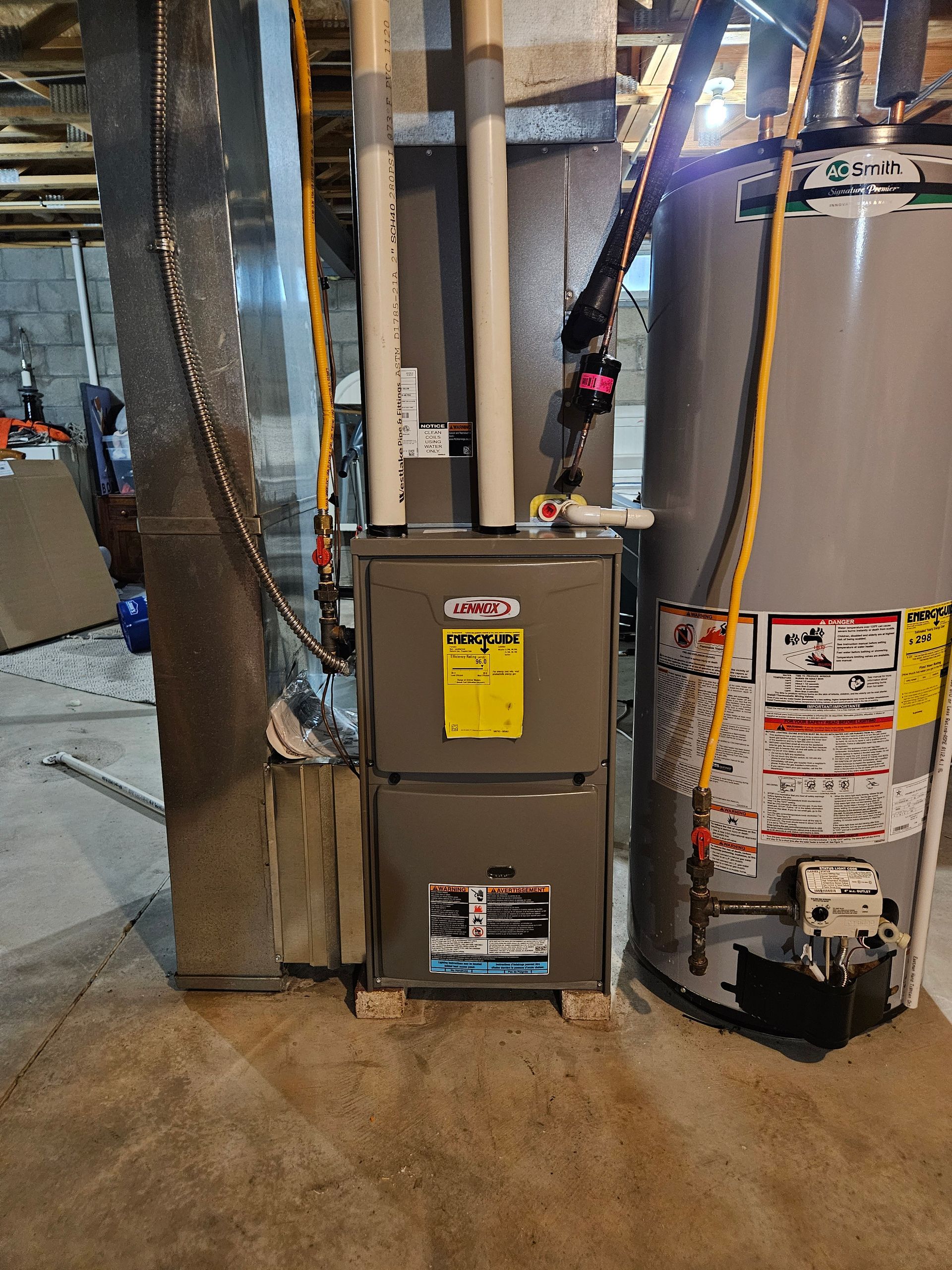 A heater and a water heater are sitting next to each other in a basement.