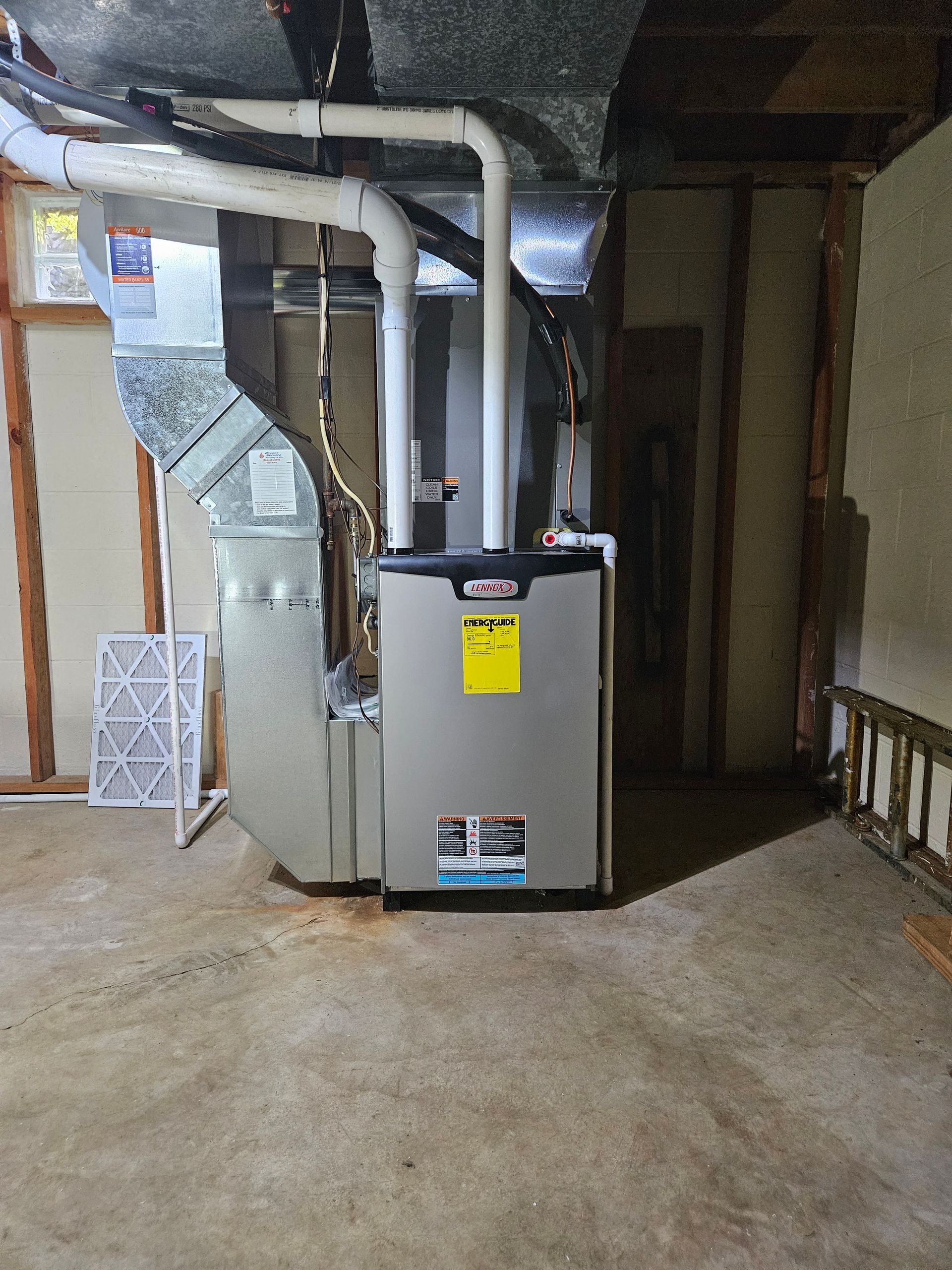 A gas heater is sitting in a basement next to a window.