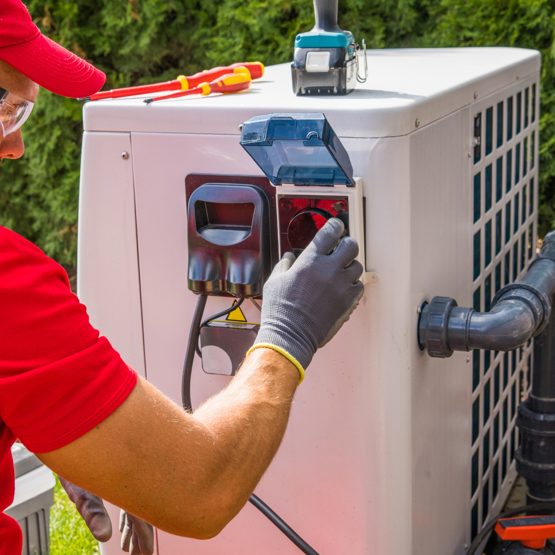 A man in a red shirt is working on an air conditioner.