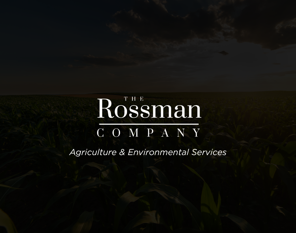 A man is working on an air conditioner with a rossman company logo in the background.