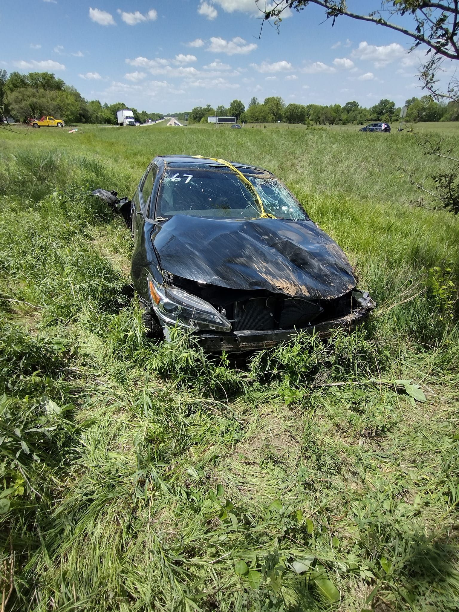 A black car is sitting in the middle of a grassy field.