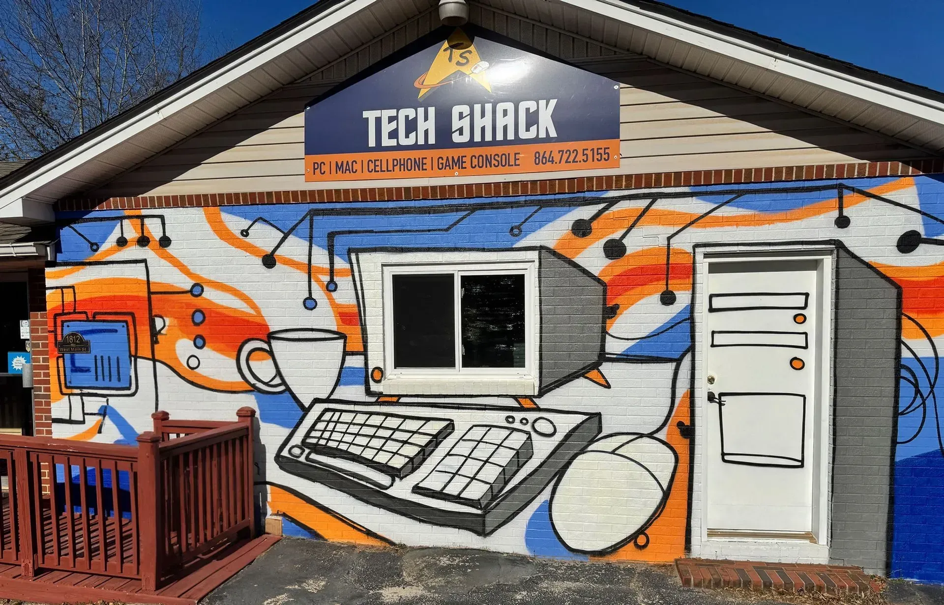 Tech Shack storefront mural with orange and blue computer graphics on a gray building