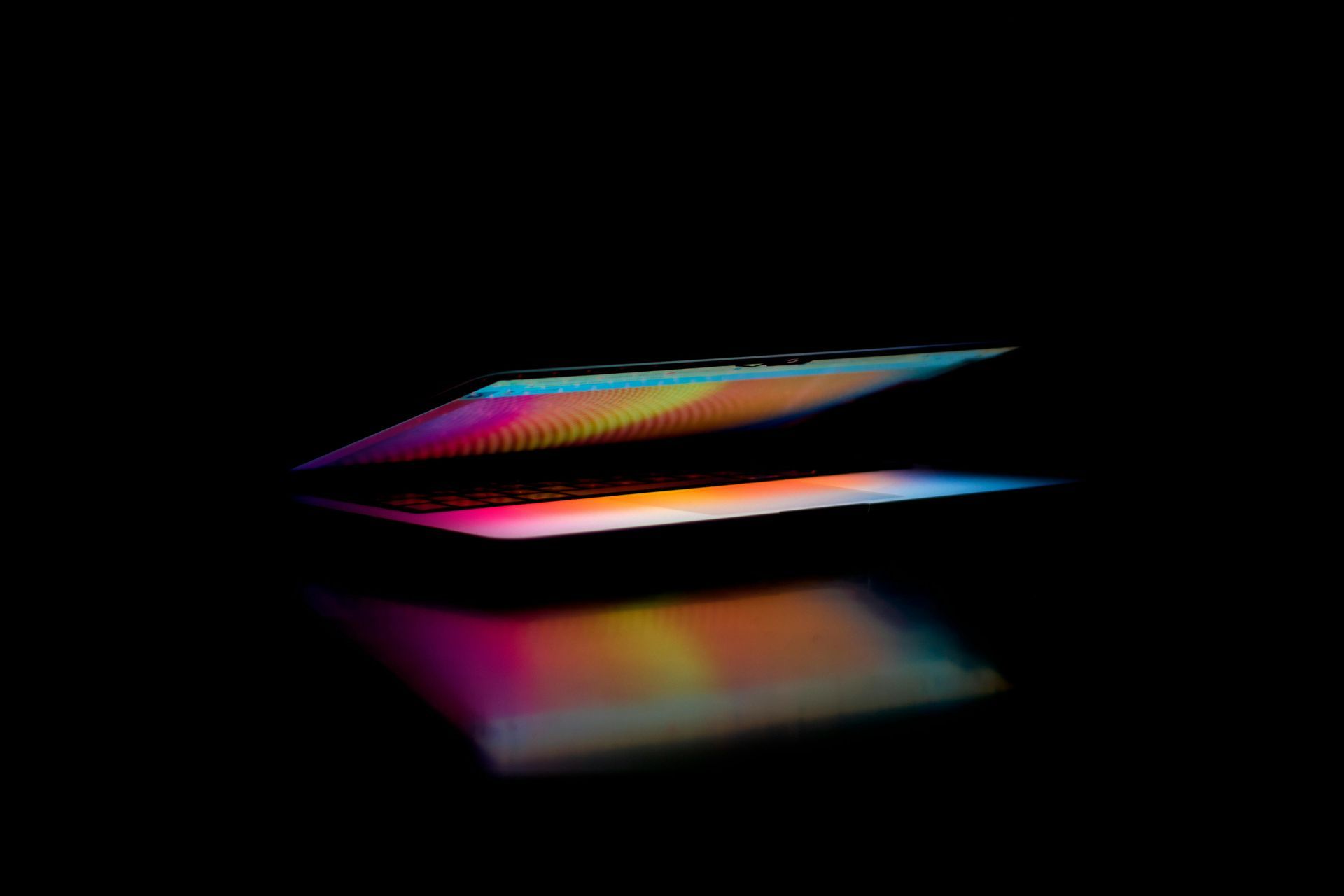 Two thin, glowing panels with vibrant, shifting gradients of purple, pink, and yellow reflected on a glossy black surface.