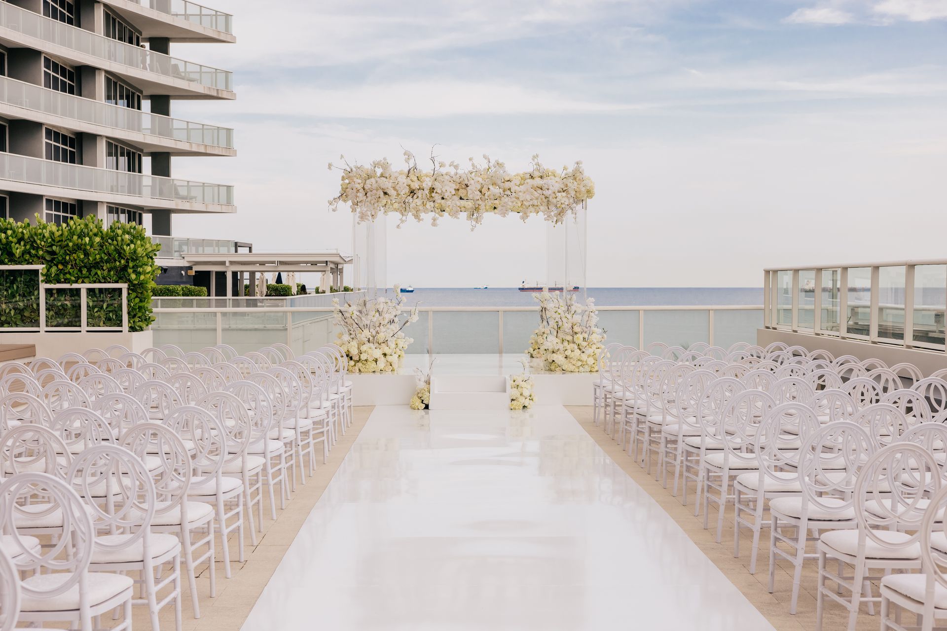 a wedding ceremony is taking place on a balcony overlooking the ocean .
