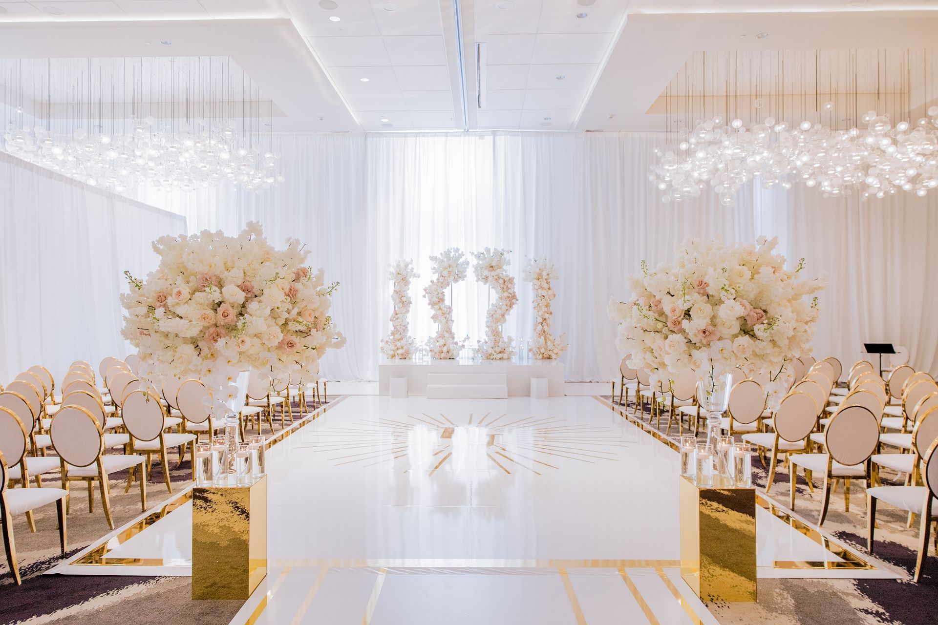 a wedding ceremony is taking place in a large room with a long white aisle .
