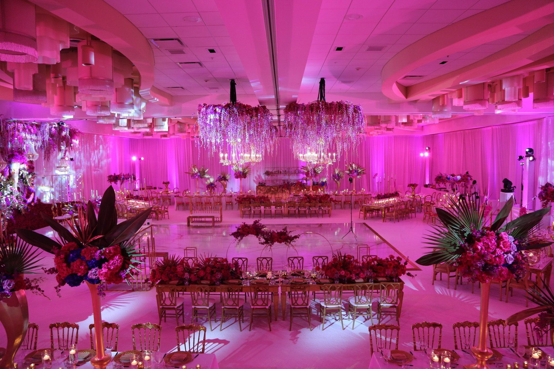 a large room decorated for a wedding with pink lights and flowers .