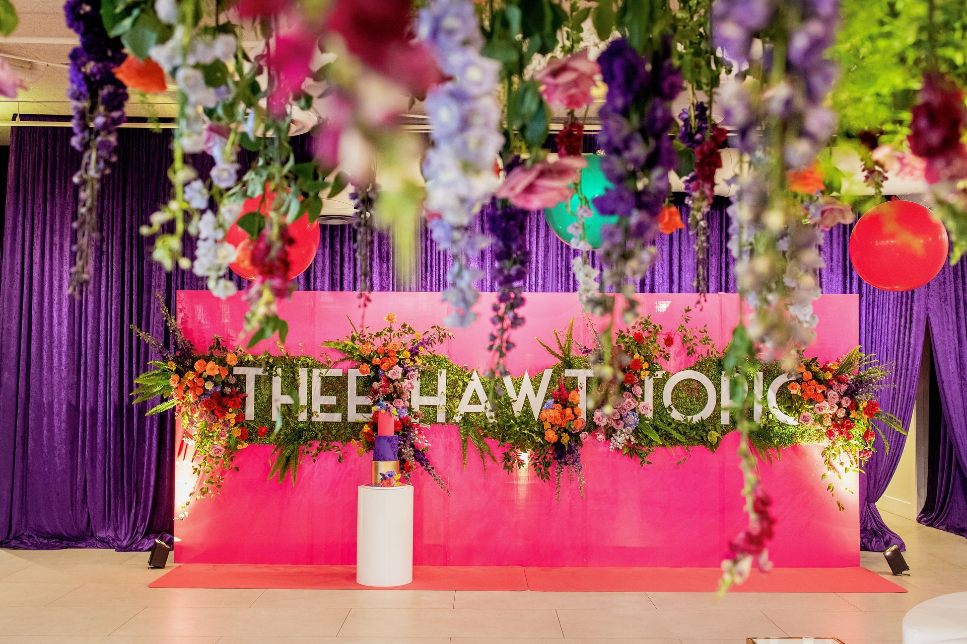 a pink wall with flowers hanging from the ceiling .