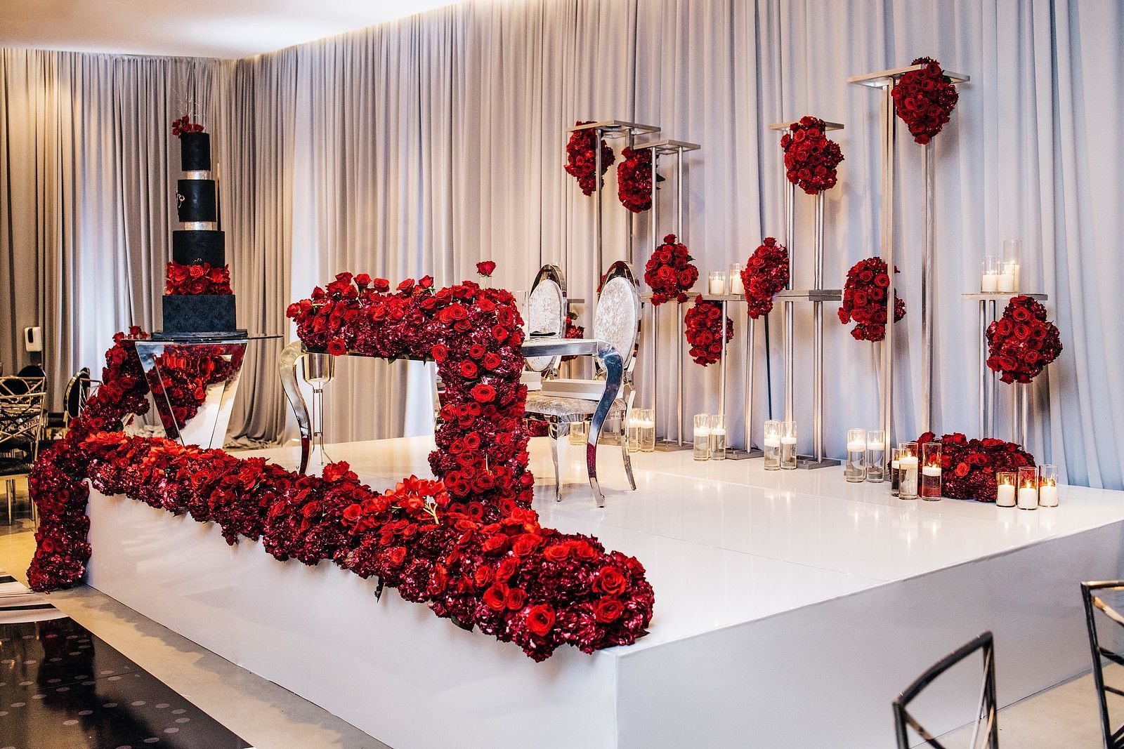 a wedding reception with a table and chairs decorated with red flowers and candles .