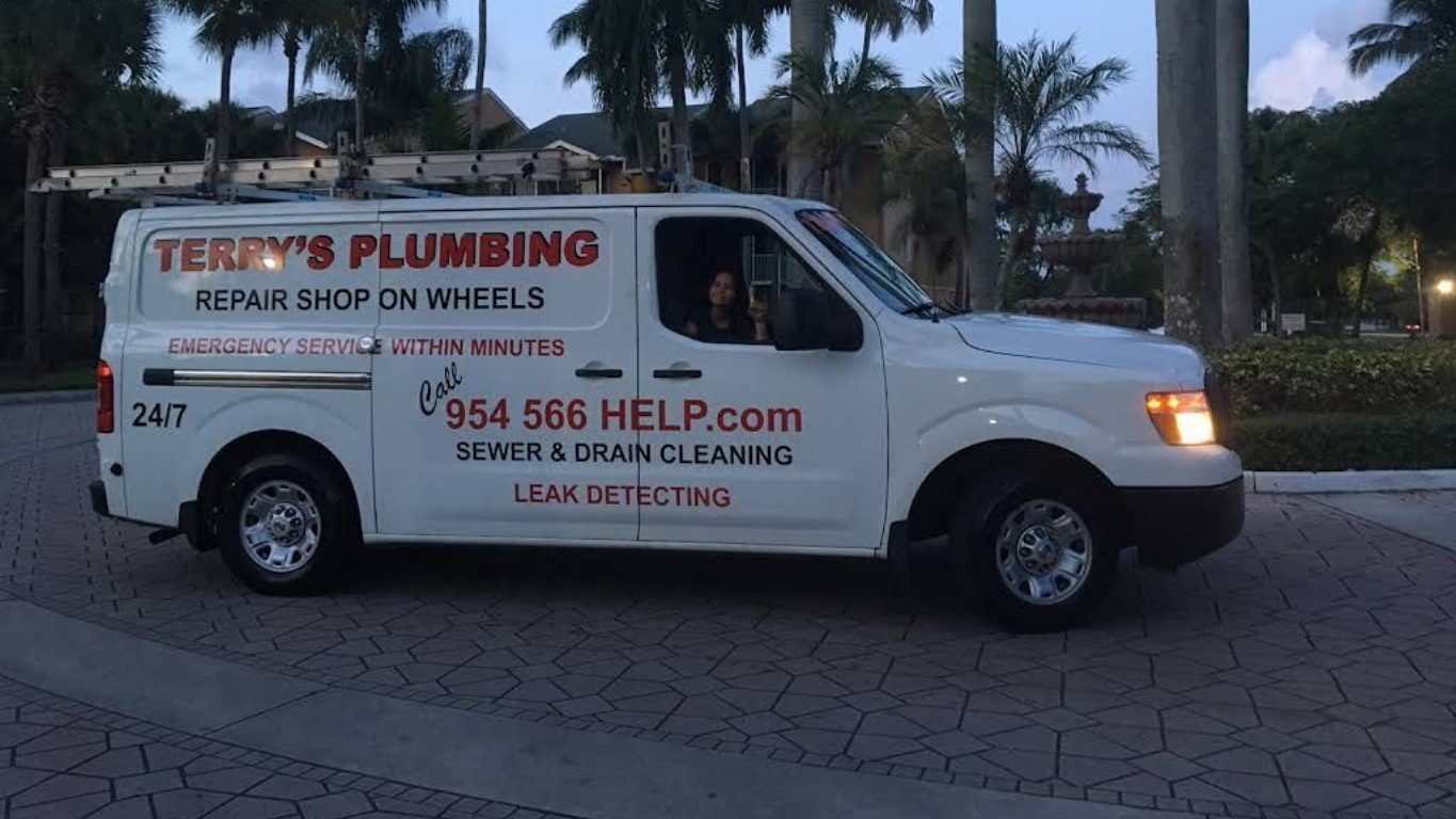 A white Terry's Plumbing service van parked on a paved driveway at dusk, with text advertising sewer and drain services.