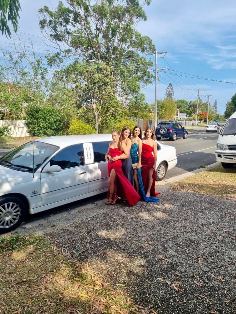 A Group of Women Are Standing in Front of a White Limousine — Noosa Premier Stretch Holden Transfers In Sunrise Beach, QLD