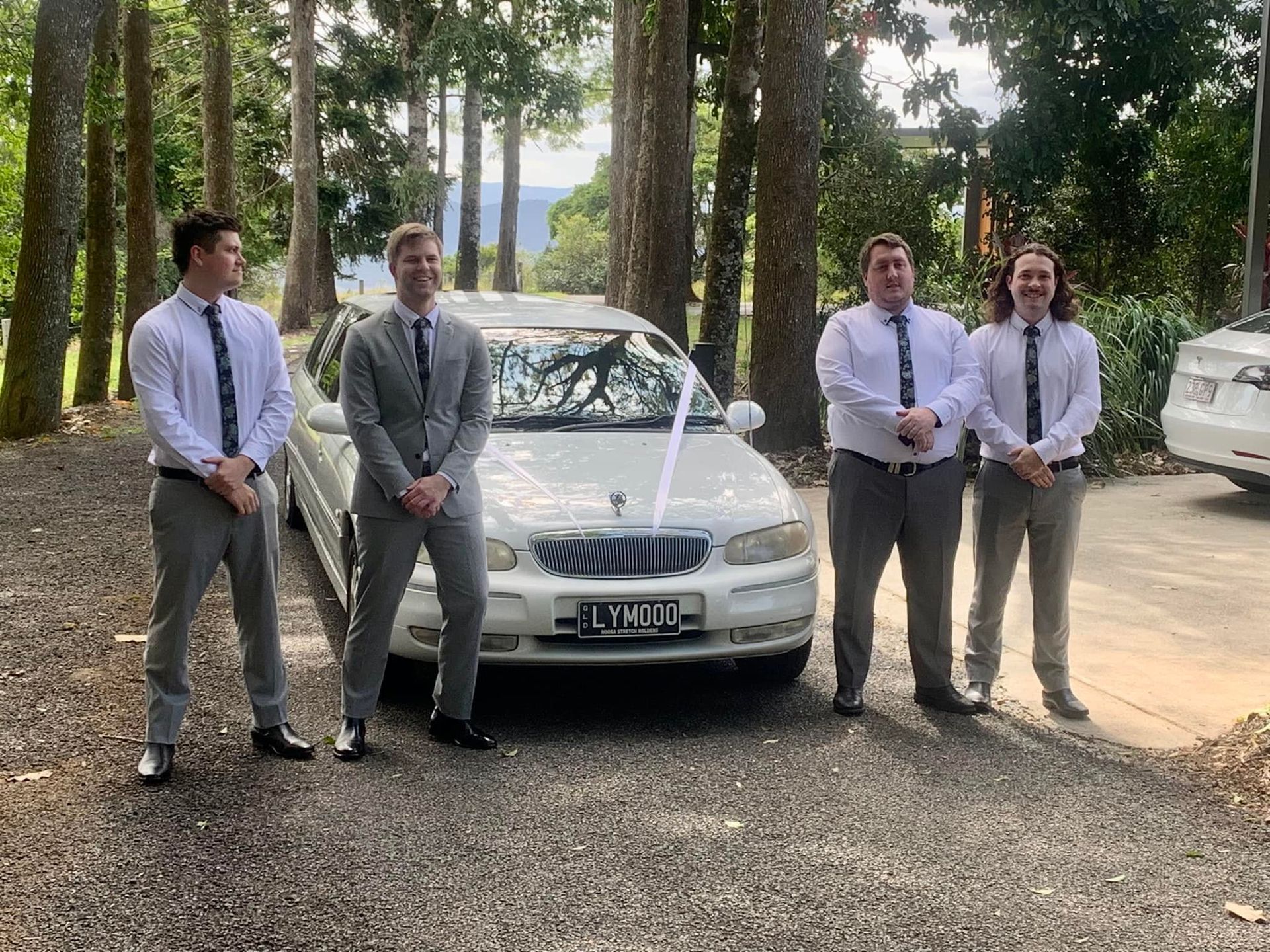 A Group of Men Are Standing in Front of a White Car — Noosa Premier Stretch Holden Transfers In Sunrise Beach, QLD