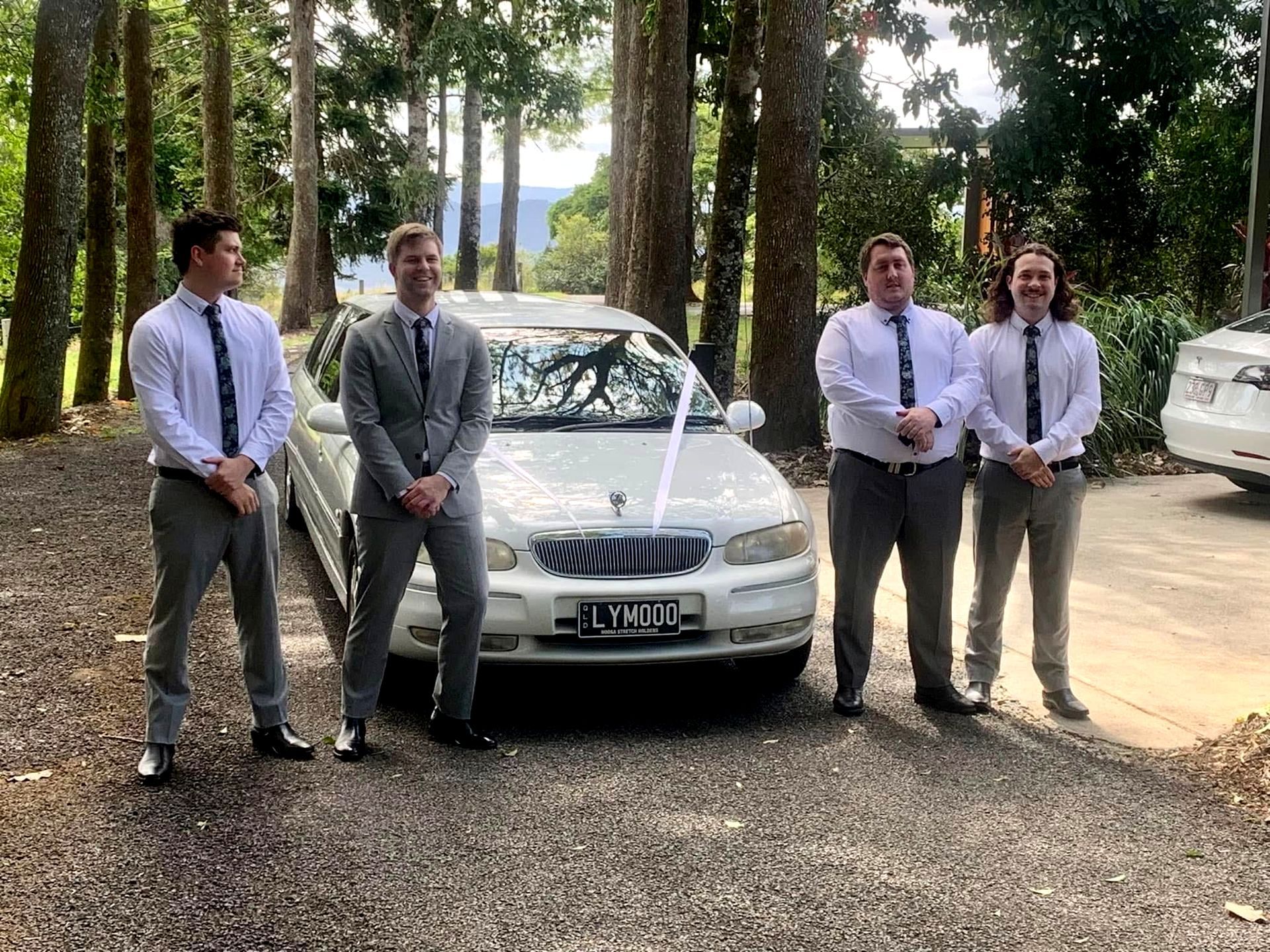Friends Dressed For Wedding, Standing In Front Of a Car And Smiling - Noosa Premier Stretch Holden Transfers In Sunrise Beach, QLD