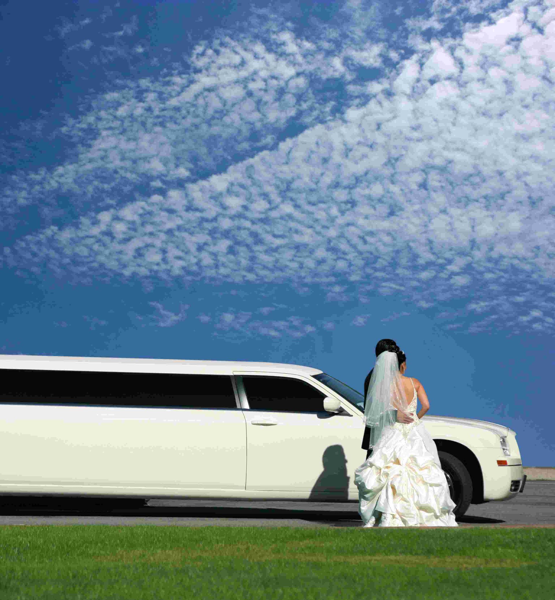 A Bride and Groom Are Standing in Front of a White Limousine — Noosa Premier Stretch Holden Transfers In Maroochydore, QLD