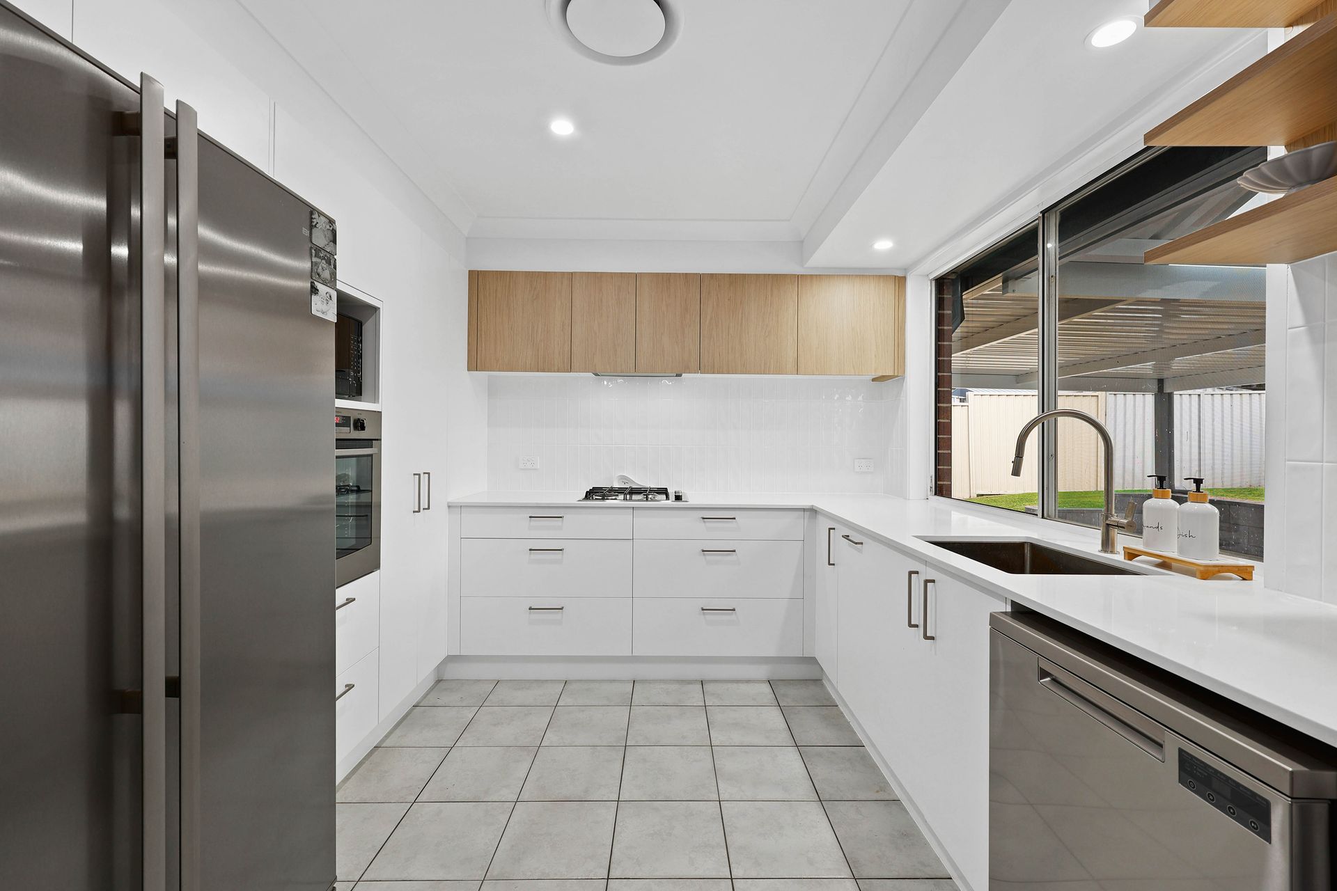 Bright kitchen with white cabinets, wooden floors, and a blue island — Above & Beyond Interiors in Smeaton Grange, NSW