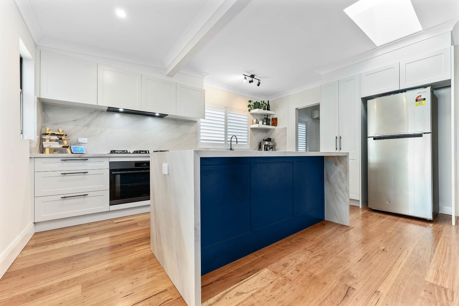 Modern Kitchen with A Blue Island, White Cabinets, and Wood Floors — Above & Beyond Interiors Custom Joinery in Bellambi, NSW