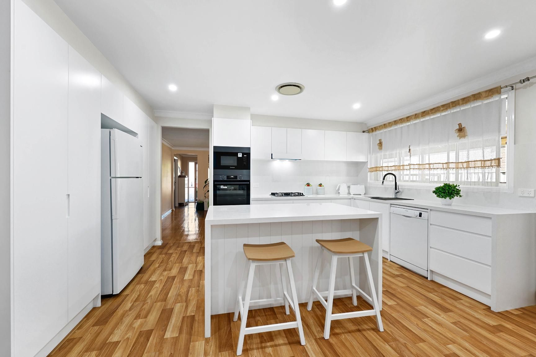 White Kitchen with Island and Bar Stools; Wooden Floor — Above & Beyond Interiors Custom Joinery in Narellan Vale, NSW