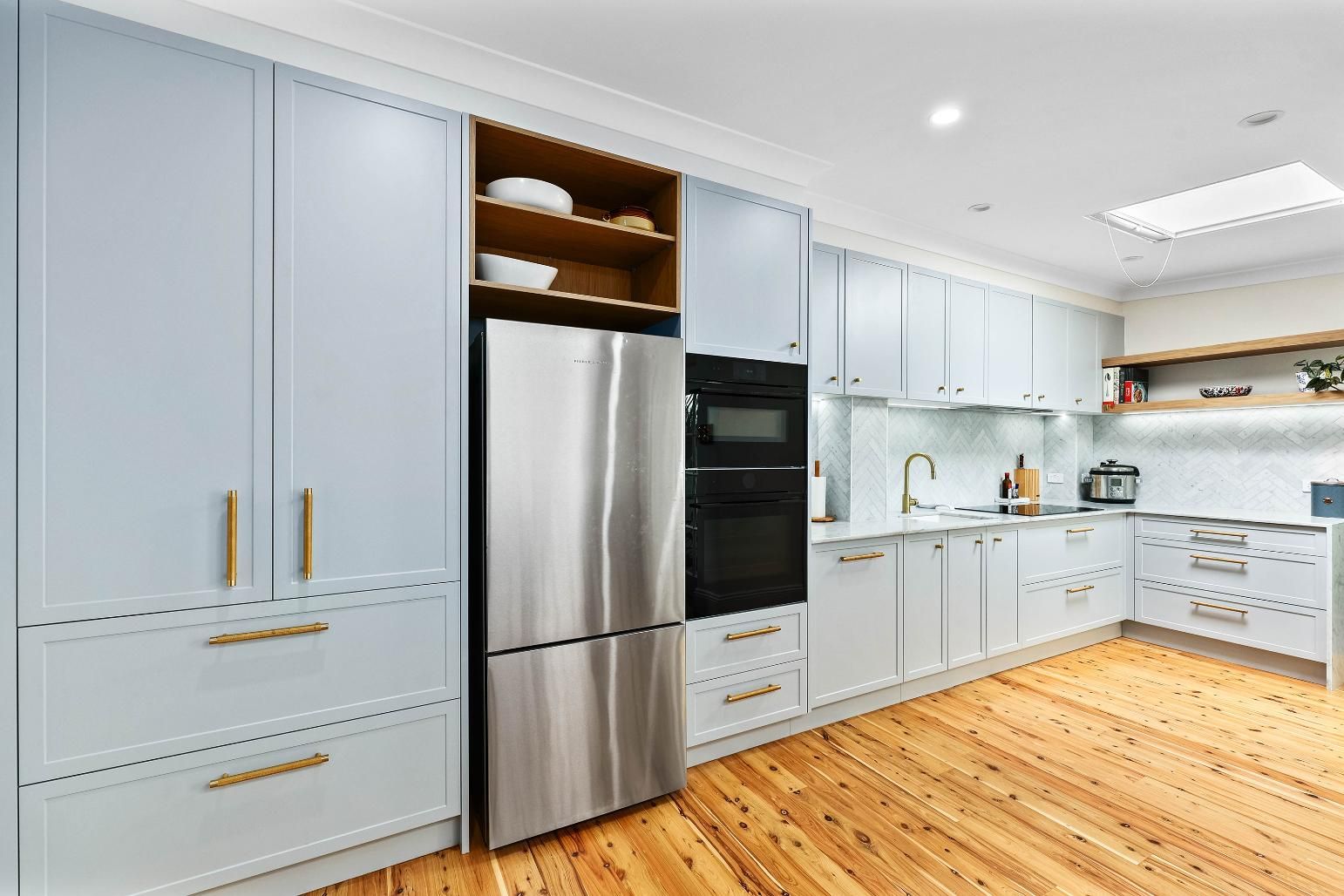 Light Blue Kitchen with Stainless Steel Refrigerator and Wooden Floors — Above & Beyond Interiors Custom Joinery in Erskineville, NSW