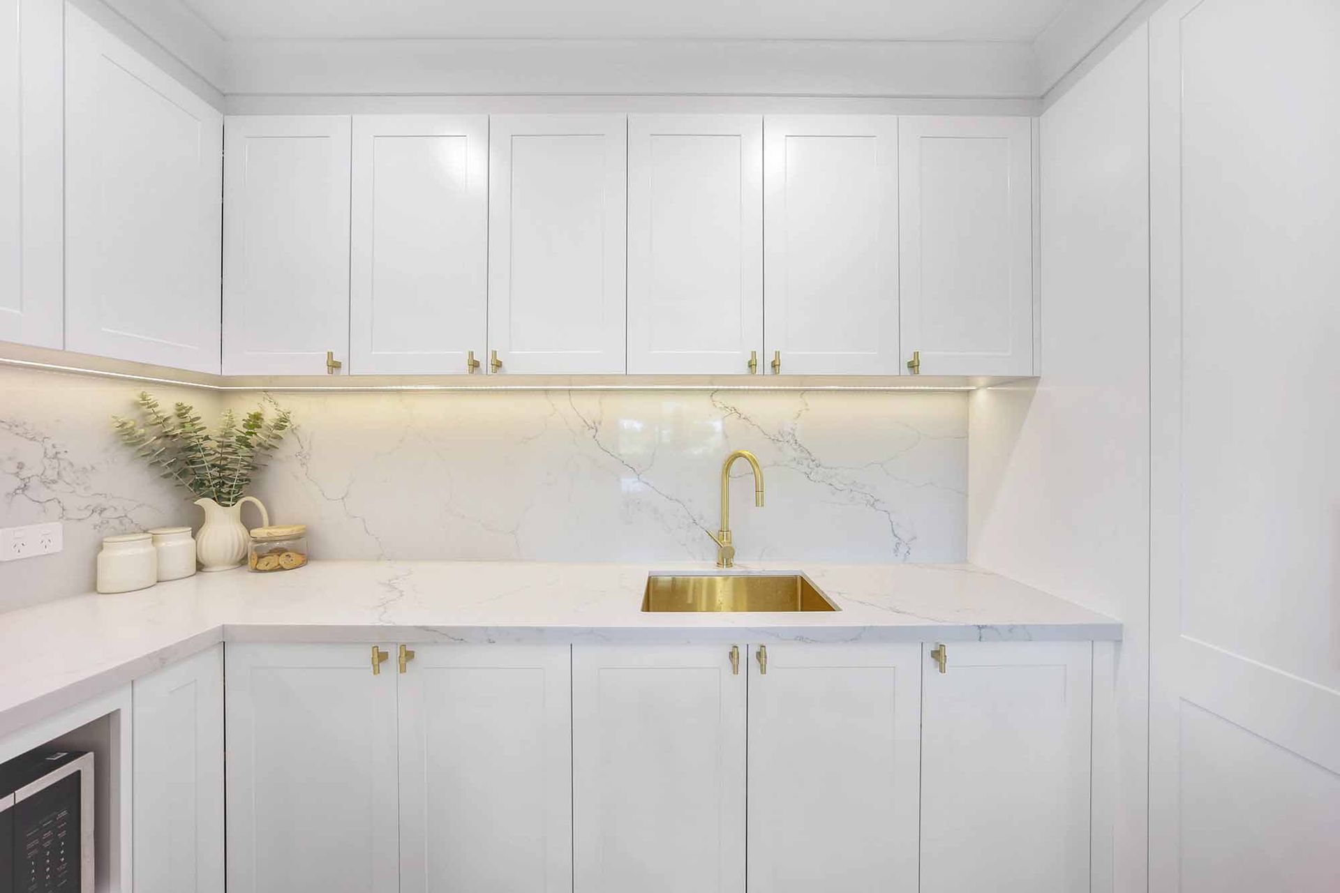 White kitchen with gold sink and fixtures, marble backsplash — Above & Beyond Interiors Custom Joinery in Bellambi, NSW
