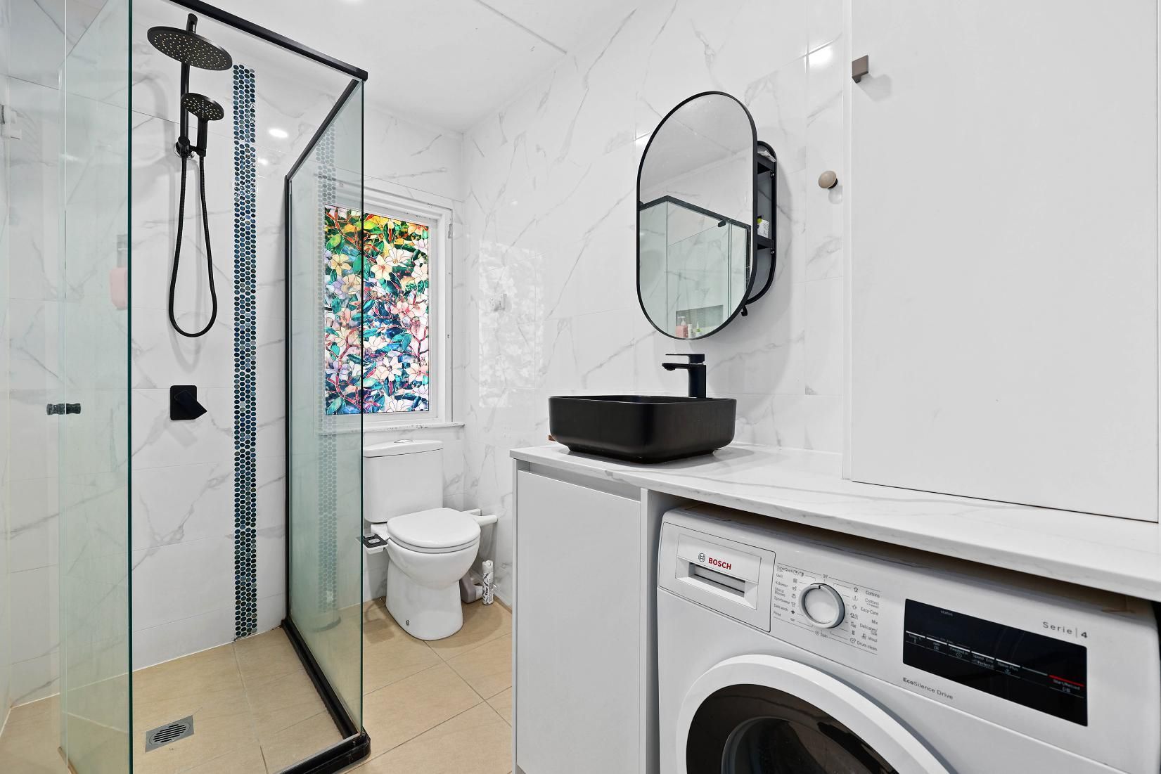 Modern Bathroom with Black Shower, Vanity Mirror, Black Sink, Toilet, and White Washing Machine — Above & Beyond Interiors Custom Joinery in Holsworthy, NSW