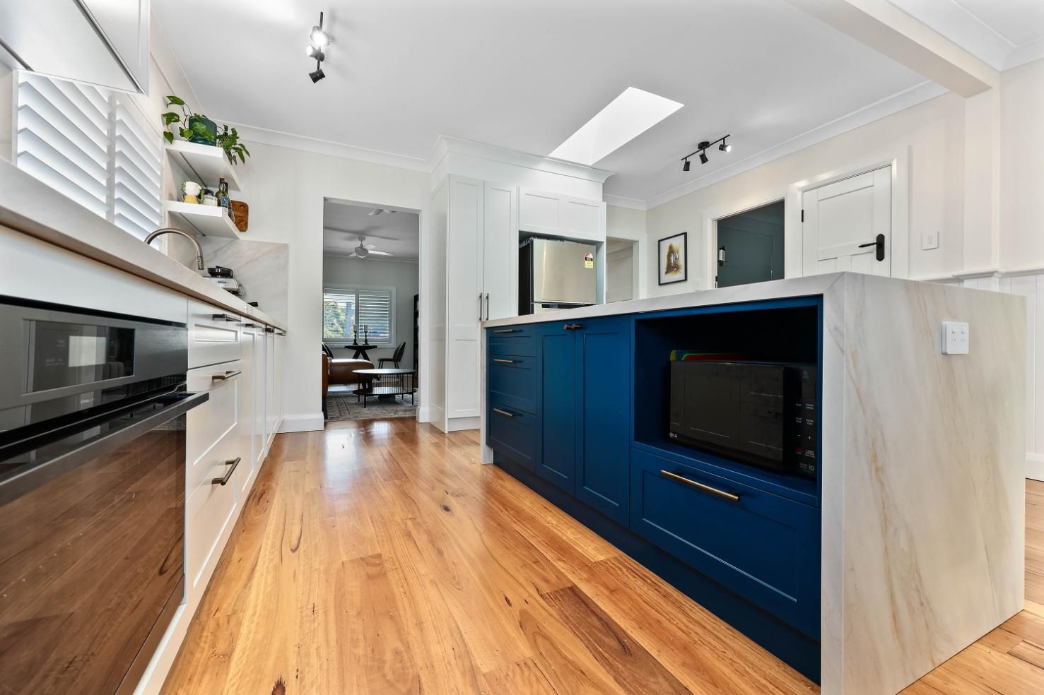 Modern Kitchen with Blue Island, Wood Floor, White Cabinets, and Stainless Steel Appliances — Above & Beyond Interiors Custom Joinery in Bellambi, NSW