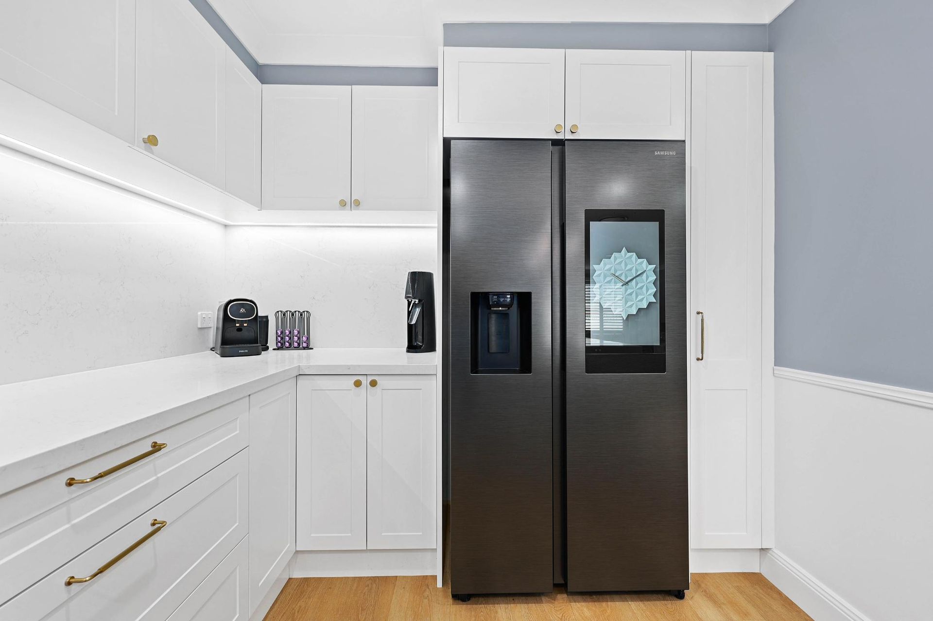 Modern White Kitchen with A Black Refrigerator, and Light Blue and White Walls — Above & Beyond Interiors Custom Joinery in Harrington Park, NSW