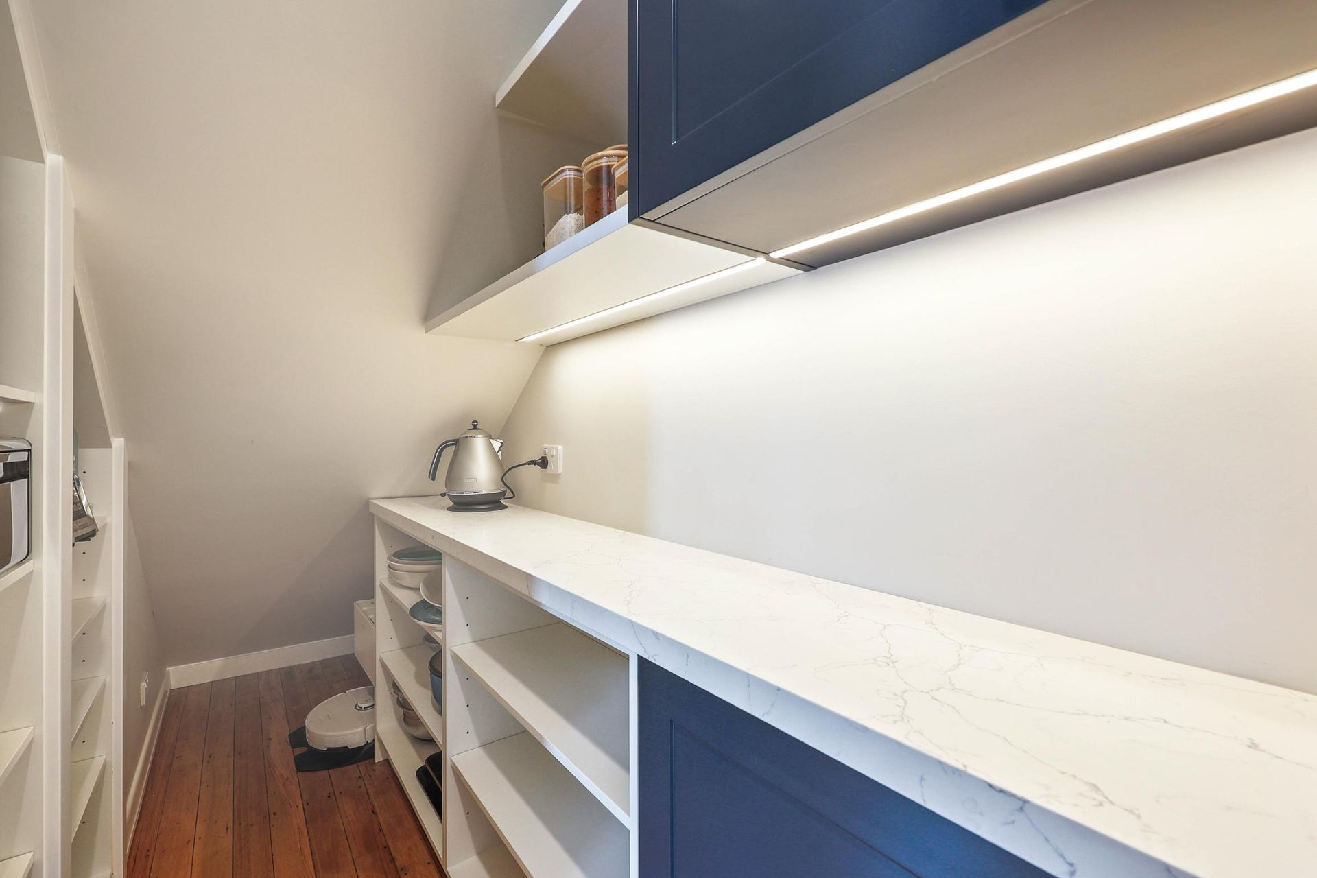 Pantry with White Shelves, Countertops, and Angled Ceiling. Dark Blue Cabinets with Under-Cabinet Lighting — Above & Beyond Interiors Custom Joinery in Lilyfield, NSW