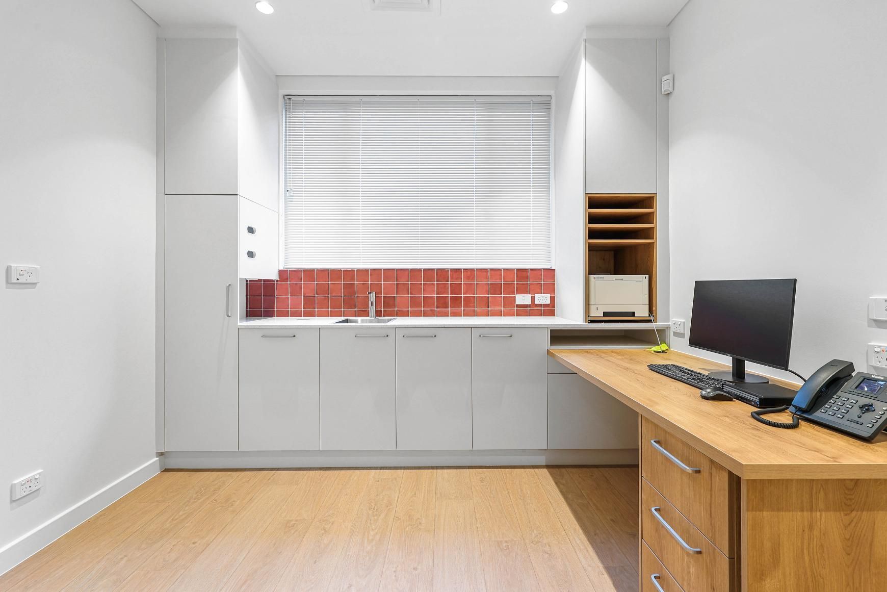 A Modern Office Space with A Desk, Cabinets, Sink, Window, and Computer — Above & Beyond Interiors Custom Joinery in Medical Centre, NSW