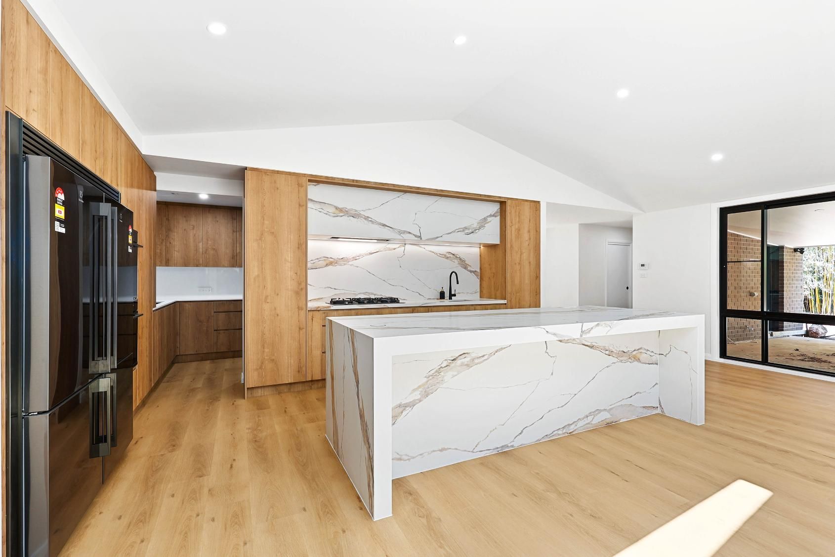 Modern Kitchen with A Large Island, Light Wood Cabinets, and Marble-Like Countertops — Above & Beyond Interiors Custom Joinery in Abbortsbury, NSW