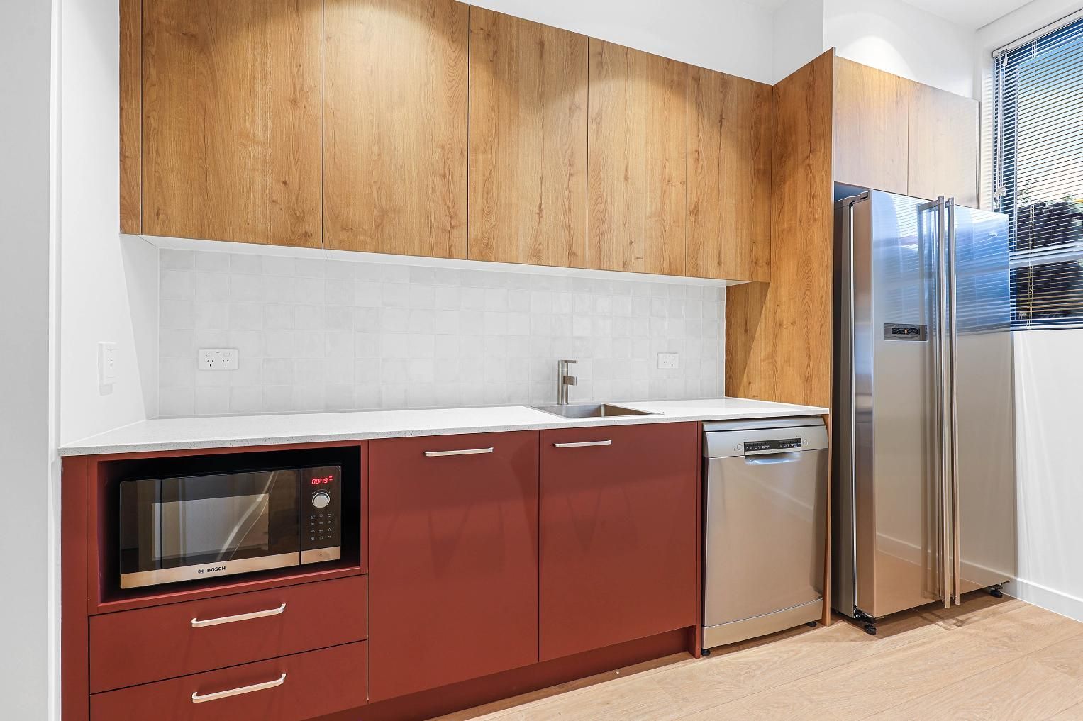 Modern Kitchen with A Stainless Steel Refrigerator, Microwave, and Red Cabinets — Above & Beyond Interiors Custom Joinery in Medical Centre, NSW