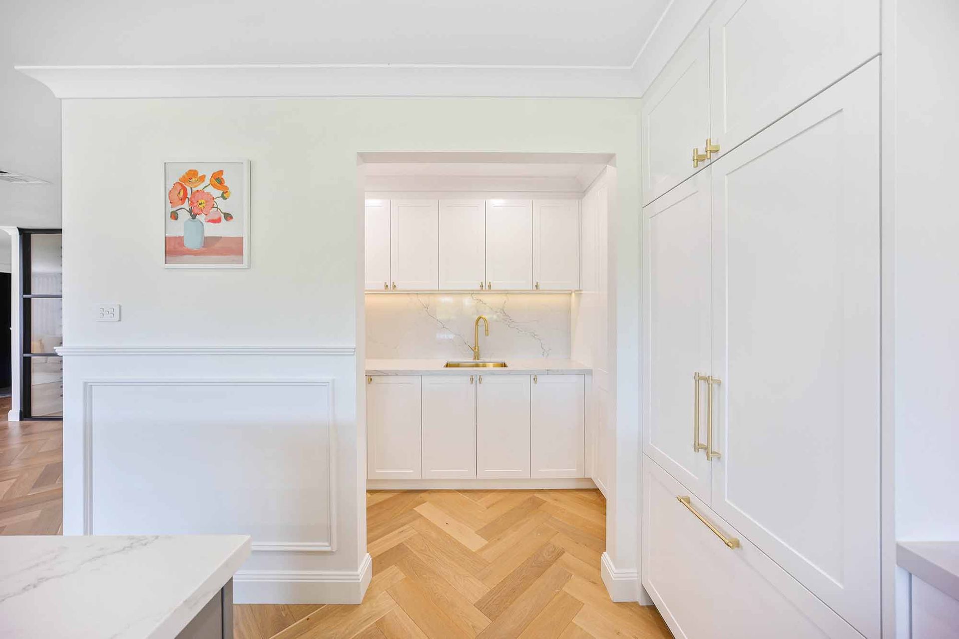 White kitchen with cabinets, herringbone floor, and a small bar area — Above & Beyond Interiors Custom Joinery in Bellambi, NSW