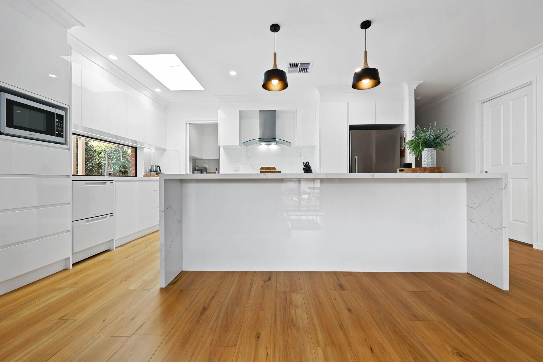 Modern White Kitchen with Wooden Floor, Island, and Pendant Lights — Above & Beyond Interiors Custom Joinery in Wattle Grove, NSW
