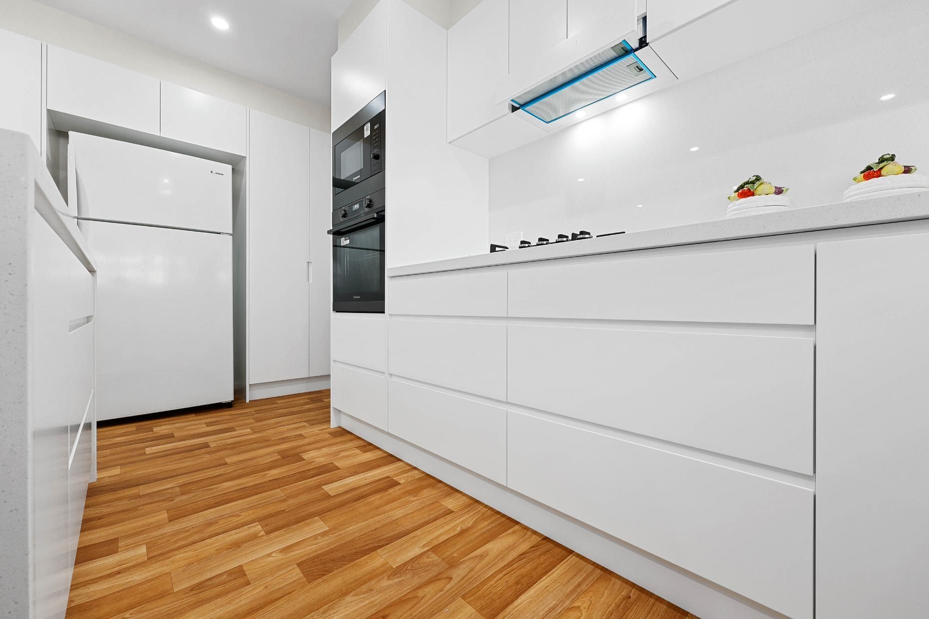 White Modern Kitchen with Wood Flooring, Cabinets, Fridge, and Stove — Above & Beyond Interiors Custom Joinery in Narellan Vale, NSW