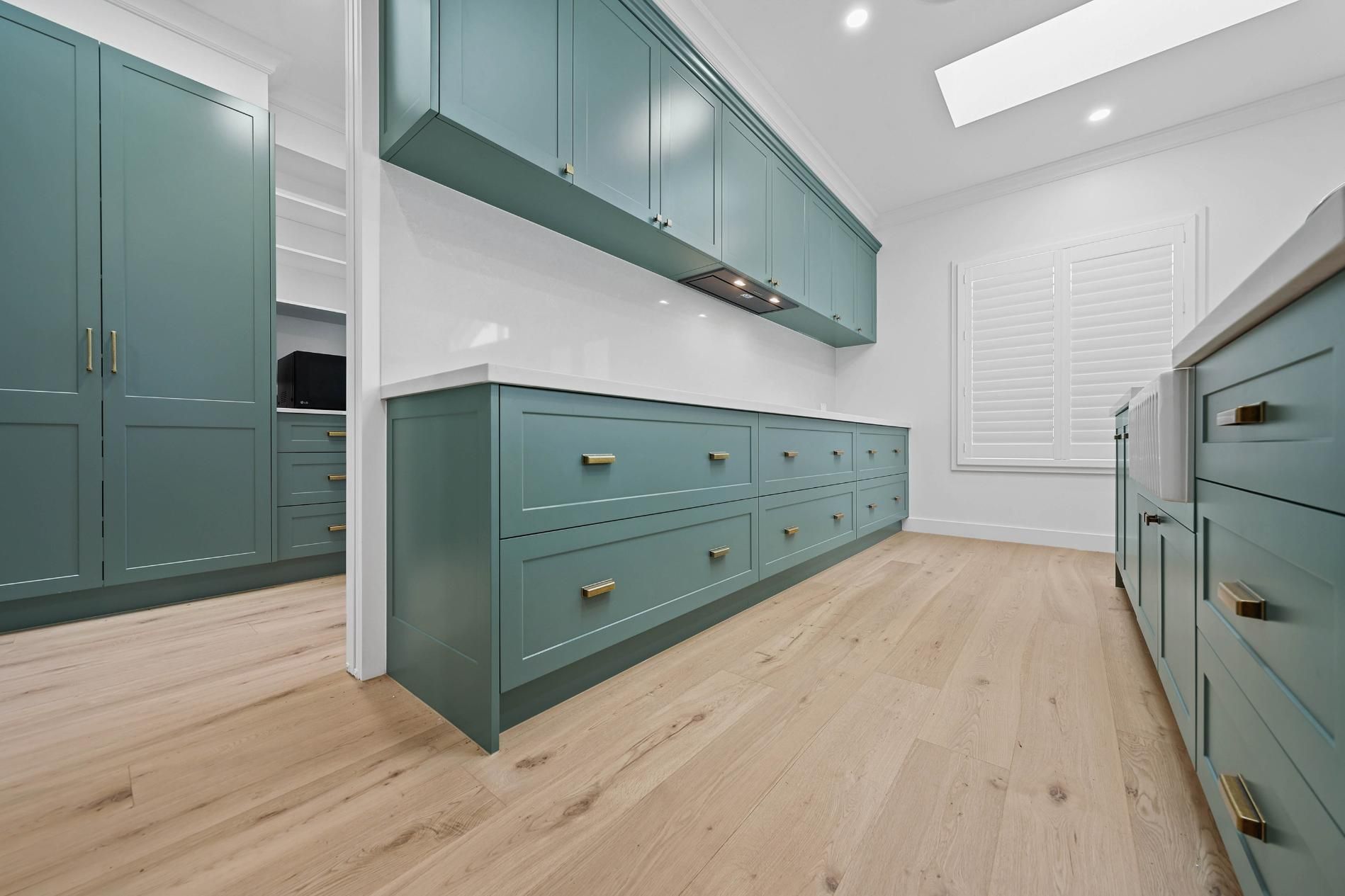 Modern Teal Kitchen with Wood Floors, White Walls, and A Skylight — Above & Beyond Interiors Custom Joinery in Appin, NSW