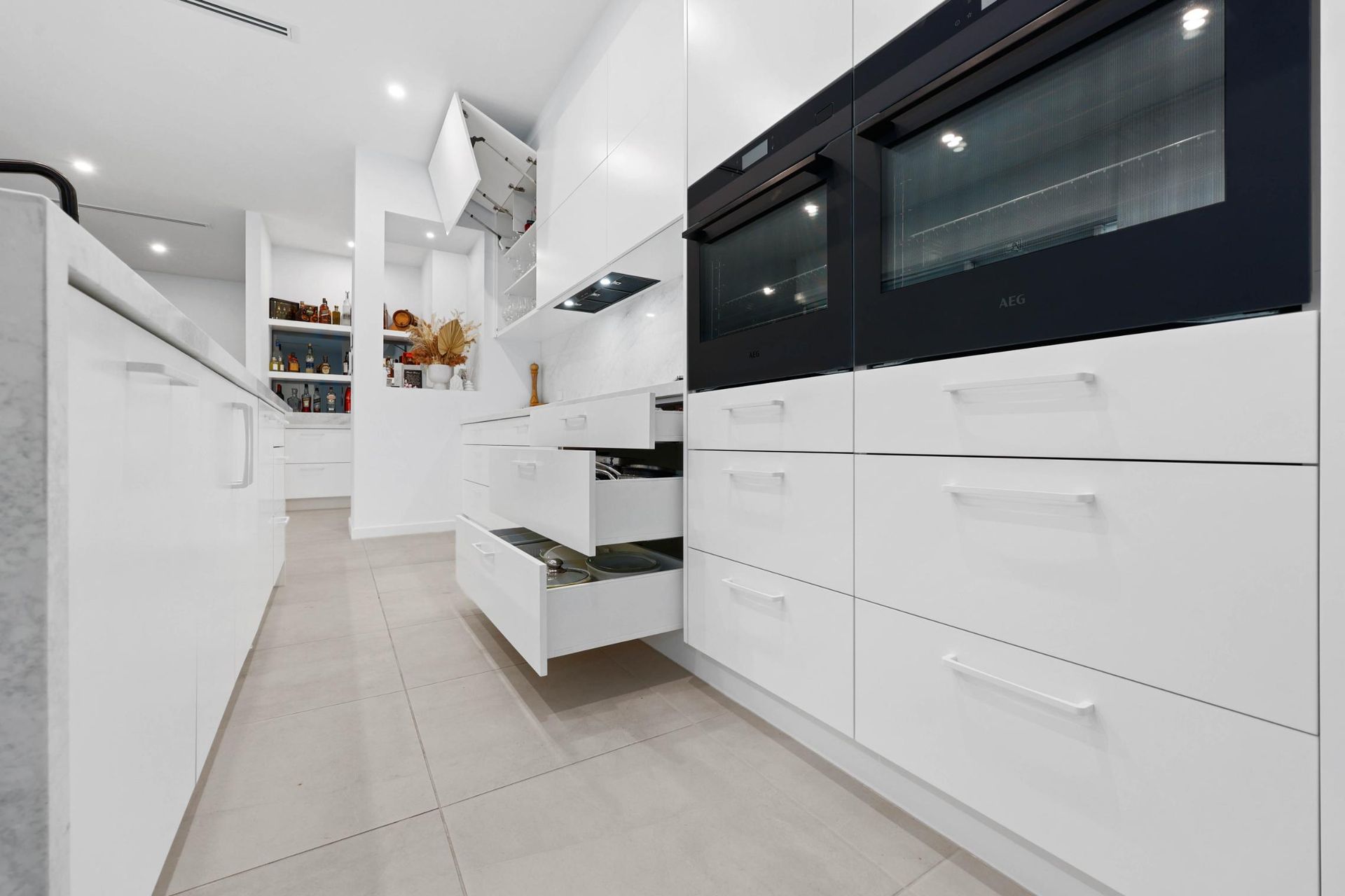 Modern White Kitchen with Open Drawers, Oven, and Counter — Above & Beyond Interiors Custom Joinery in Currans Hill, NSW