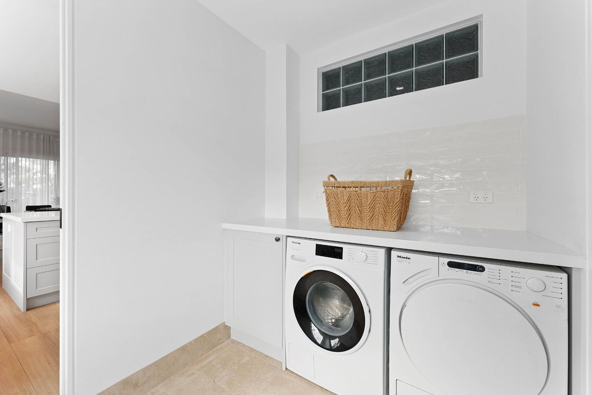 Laundry Room with White Walls, Appliances, and A Woven Basket on A Countertop Under a Small Window — Above & Beyond Interiors Custom Joinery in Yowie Bay, NSW