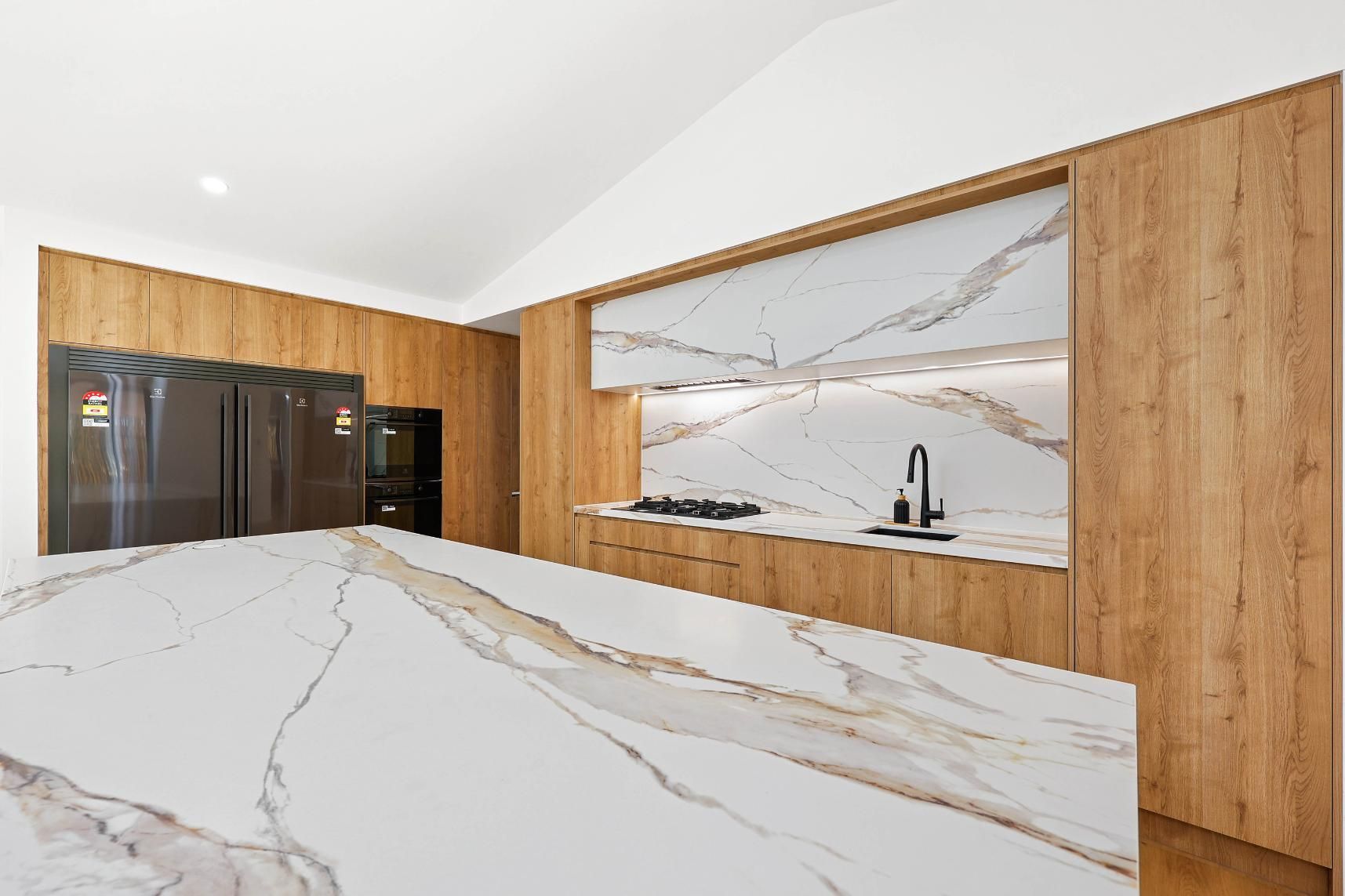 Modern Kitchen with White Marble Countertops and Light Wood Cabinetry — Above & Beyond Interiors Custom Joinery in Abbortsbury, NSW