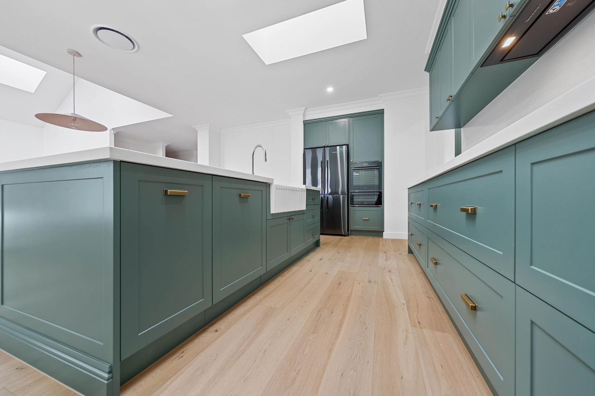 Green Kitchen Cabinetry with Light Wood Floors, White Countertops, and A Skylight — Above & Beyond Interiors Custom Joinery in Appin, NSW