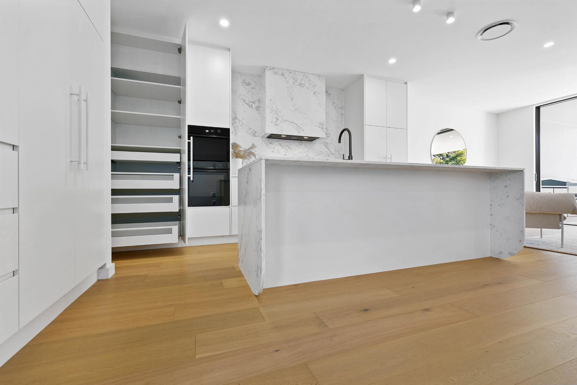 Modern White Kitchen with Marble Accents, Wooden Floors, and Open Pantry — Above & Beyond Interiors Custom Joinery in Thirroul, NSW