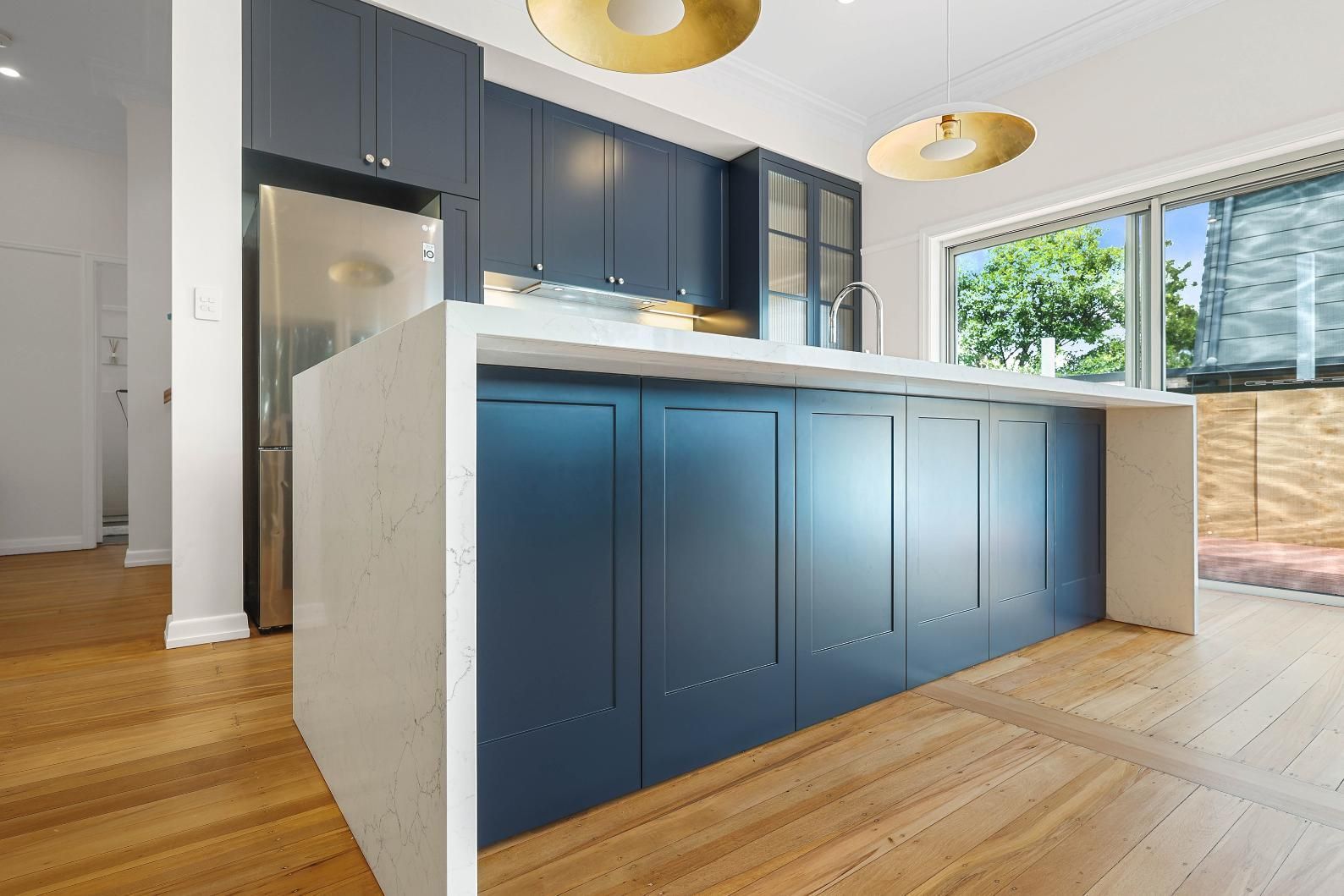 Blue Kitchen with Island and White Countertop, Wooden Floors, and A Large Window — Above & Beyond Interiors Custom Joinery in Lilyfield, NSW