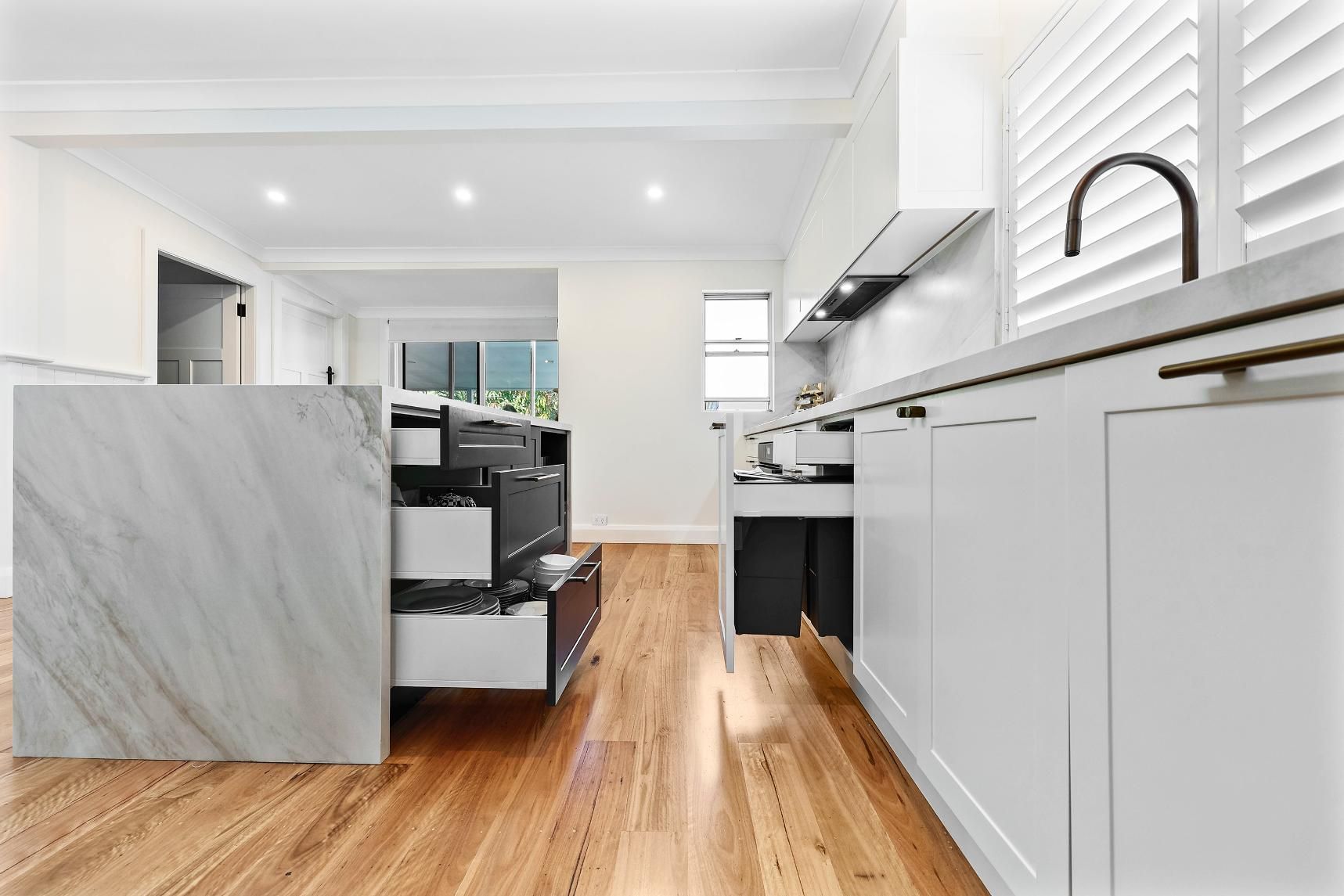 Modern White Kitchen with Marble Island and Open Drawers Revealing Storage — Above & Beyond Interiors Custom Joinery in Bellambi, NSW