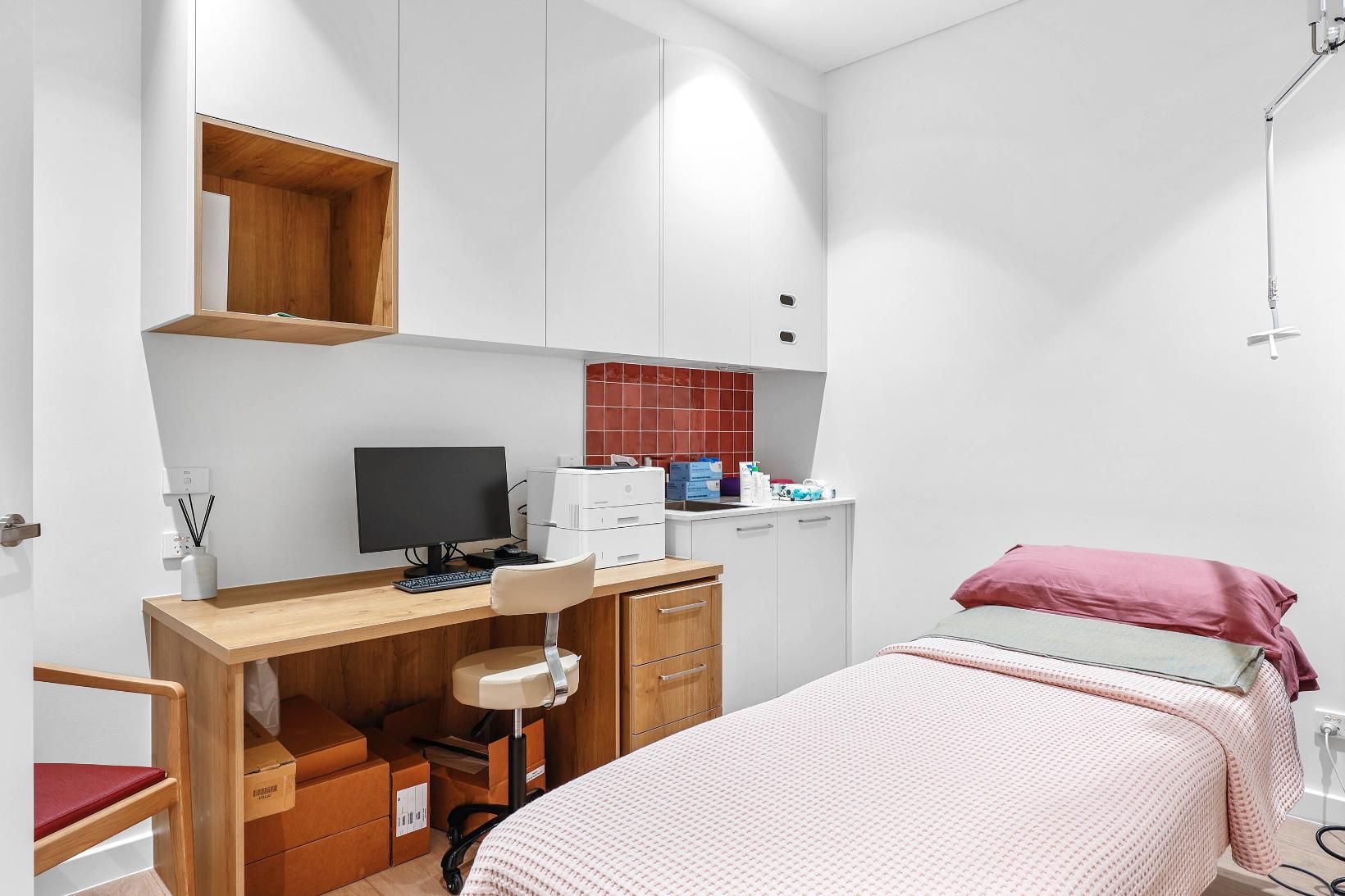 Examination Room with Desk, Computer, Chair, Bed, and Storage Cabinets; White and Wood Tones — Above & Beyond Interiors Custom Joinery in Medical Centre, NSW