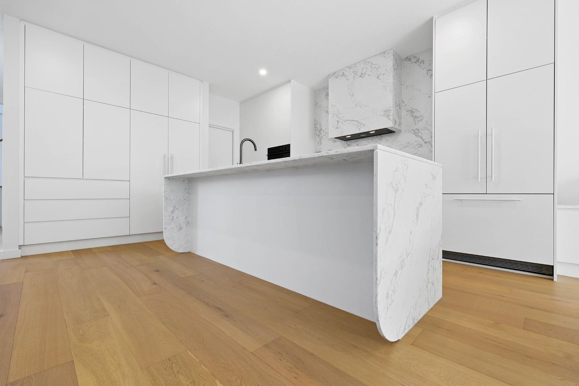Modern White Kitchen with Island, Cabinets, and Wood Floor — Above & Beyond Interiors Custom Joinery in Thirroul, NSW