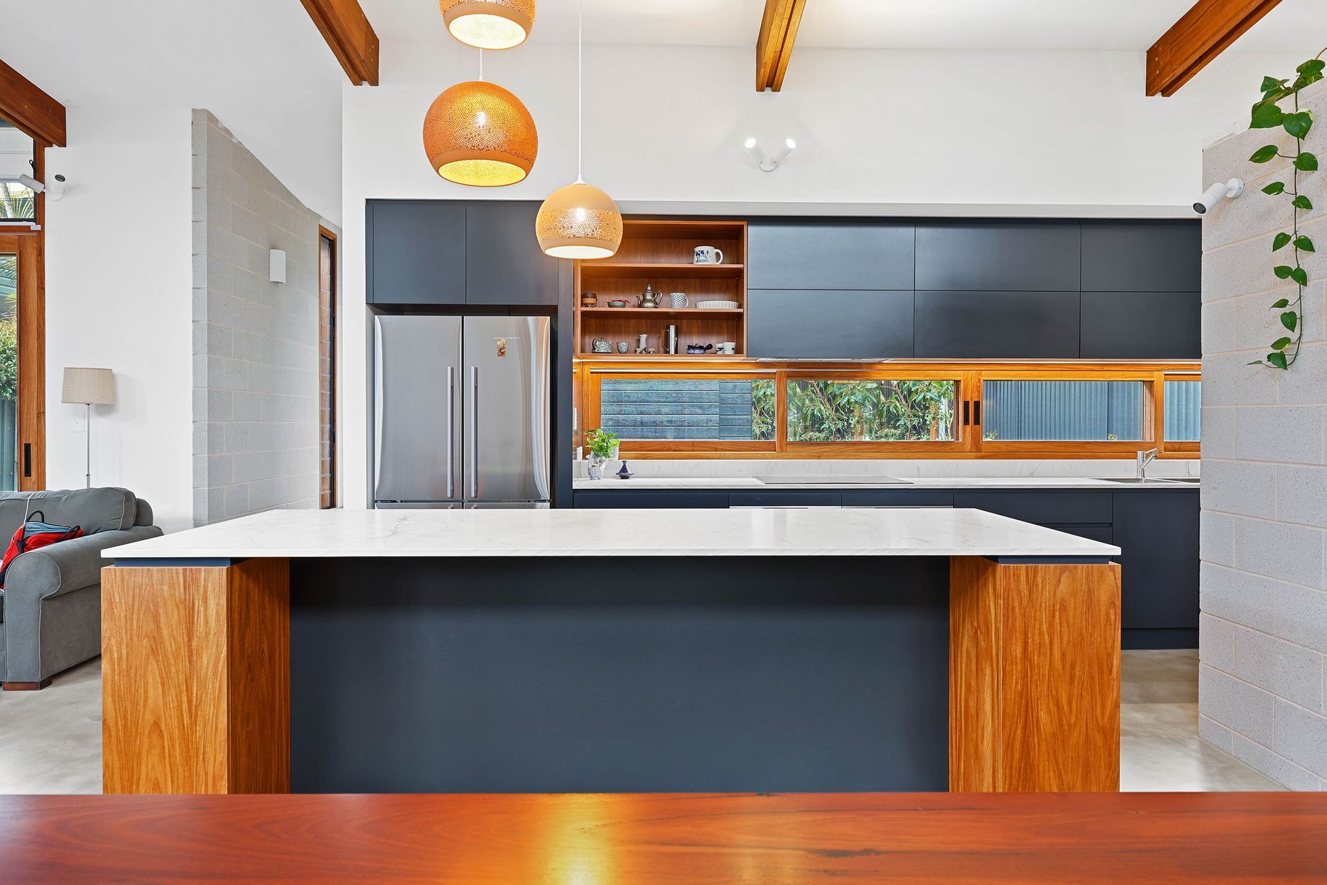 Modern kitchen with dark blue cabinets, wood accents, and island — Above & Beyond Interiors Custom Joinery in Bellambi, NSW