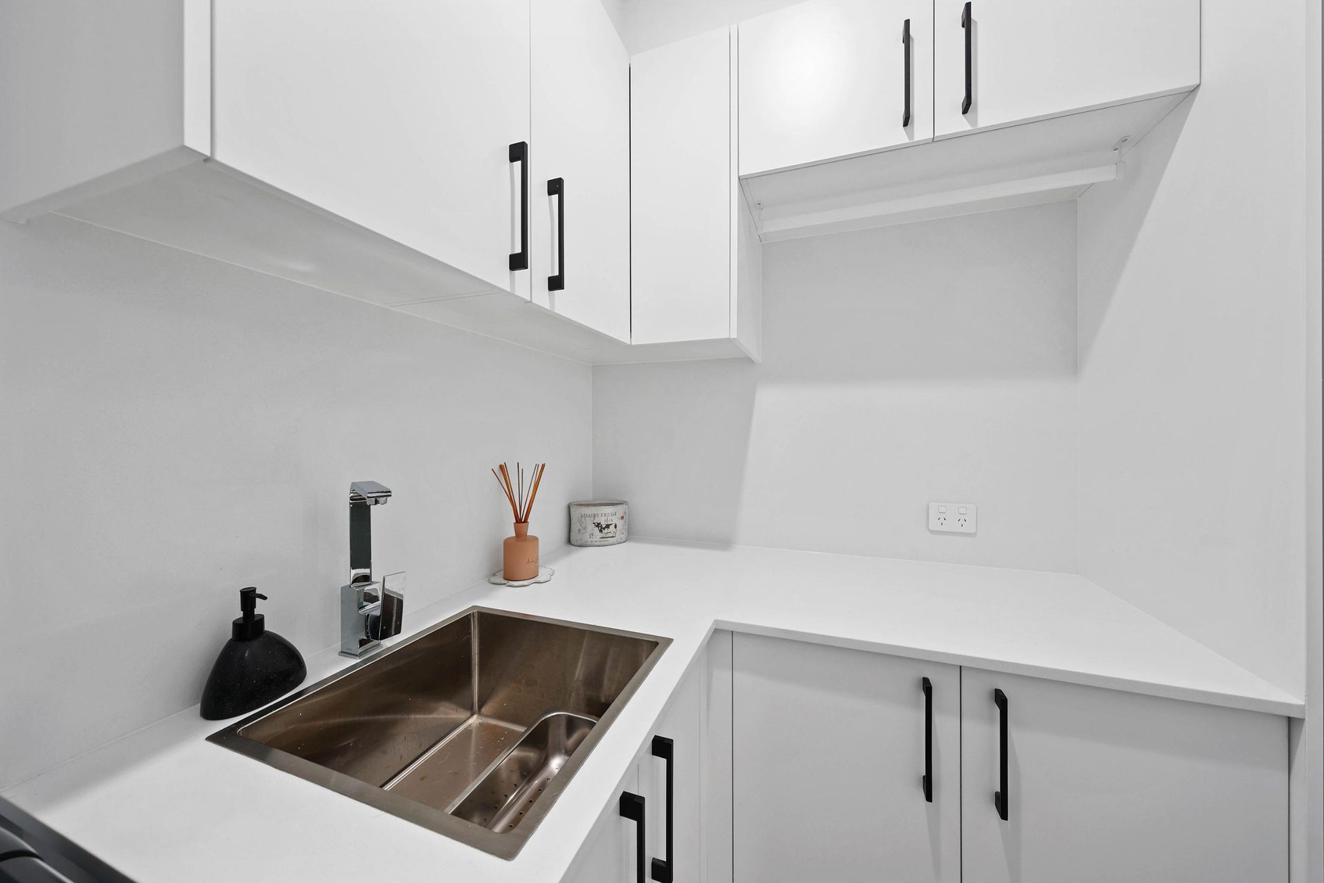 White Laundry Room with Cabinets, Sink, and Countertop, Black Hardware — Above & Beyond Interiors Custom Joinery in Bradbury, NSW