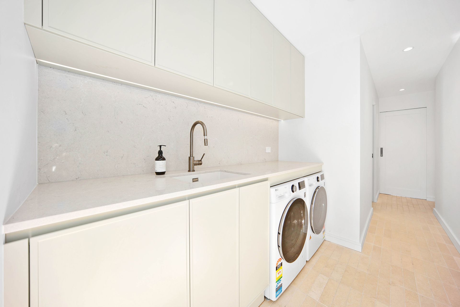 Modern laundry room with white cabinets, sink, washer and dryer — Above & Beyond Interiors Custom Joinery in Bellambi, NSW